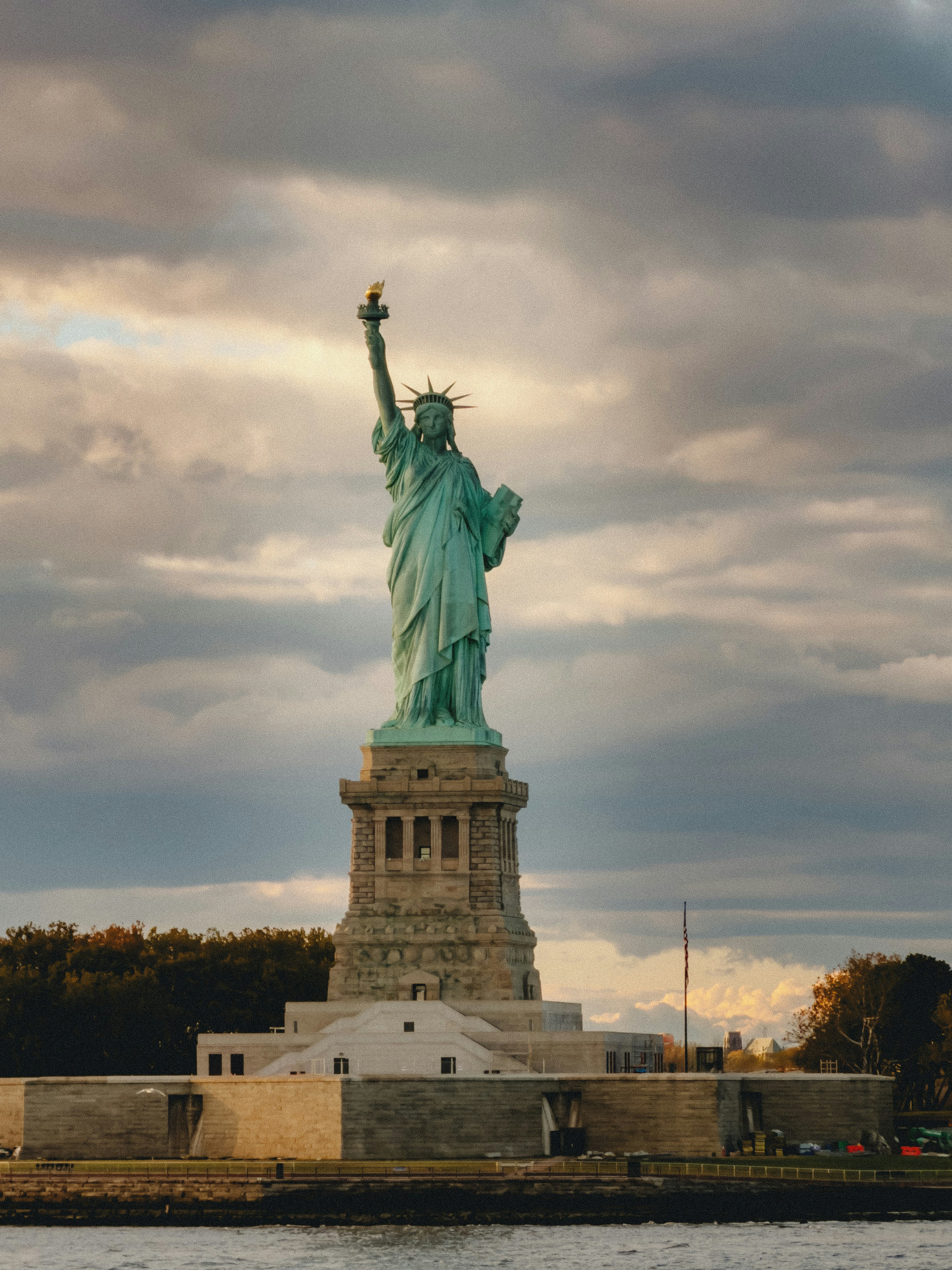 The statue of liberty stands tall against cloudy sky.