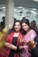 Two women smiling at the camera indoors