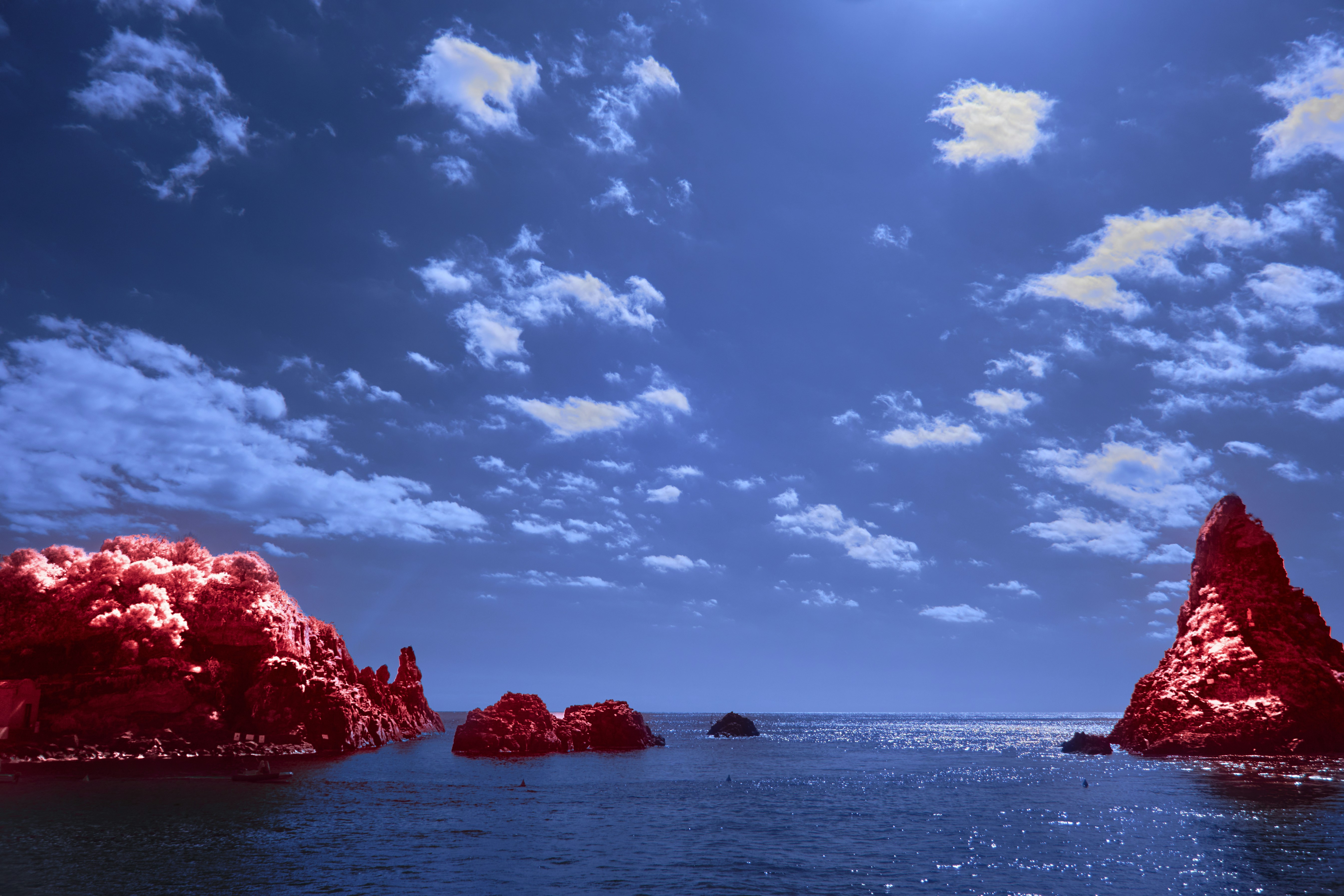 Red rocky islands in the blue ocean and sky
