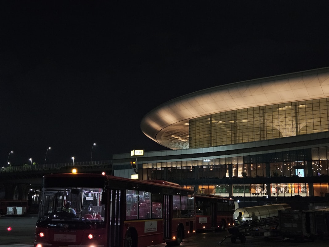 夜間亮著燈的機場航廈外觀與停靠的接駁車