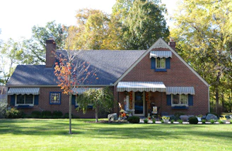A brick house with a green lawn and trees.