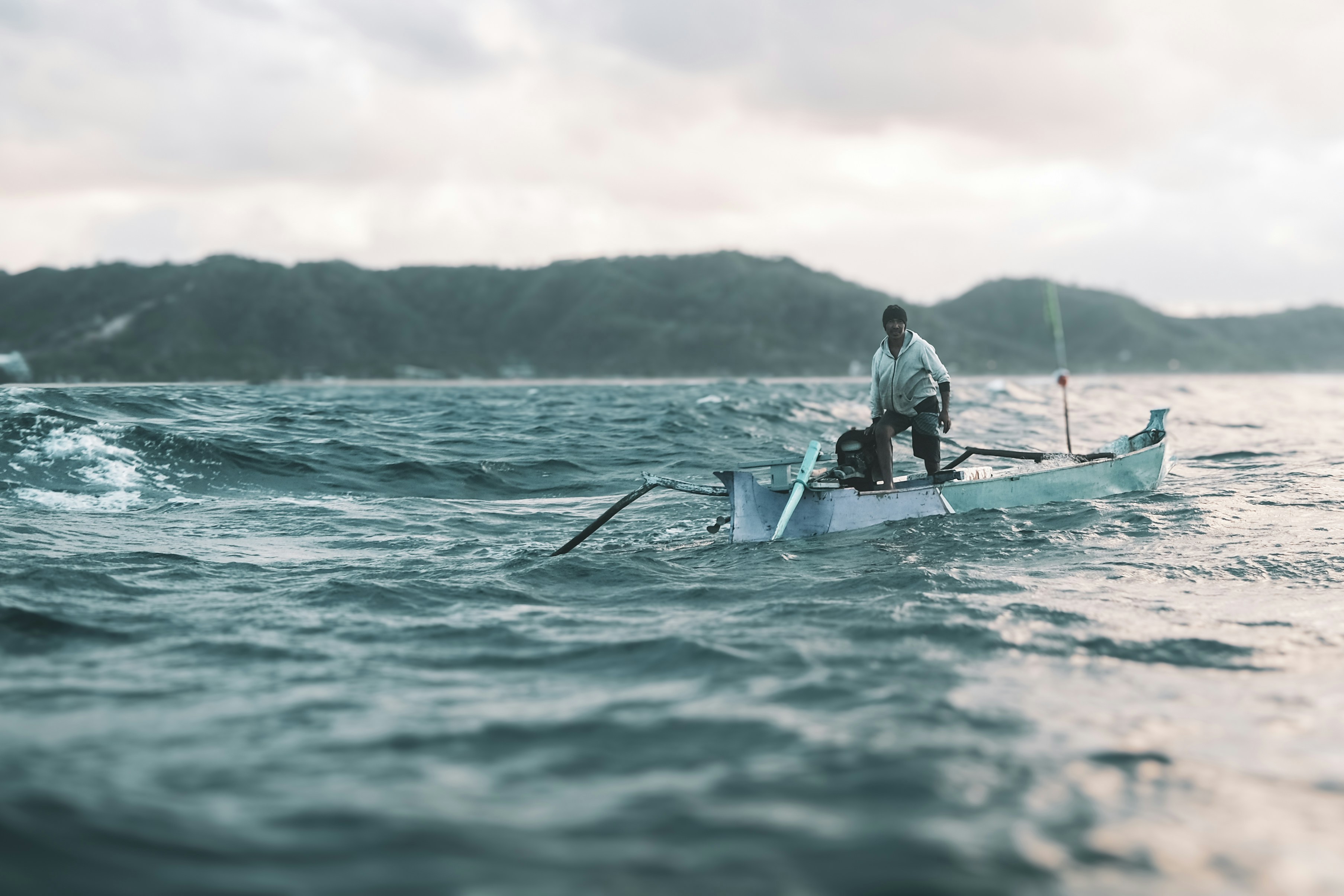 Man rowing a small boat on choppy seas