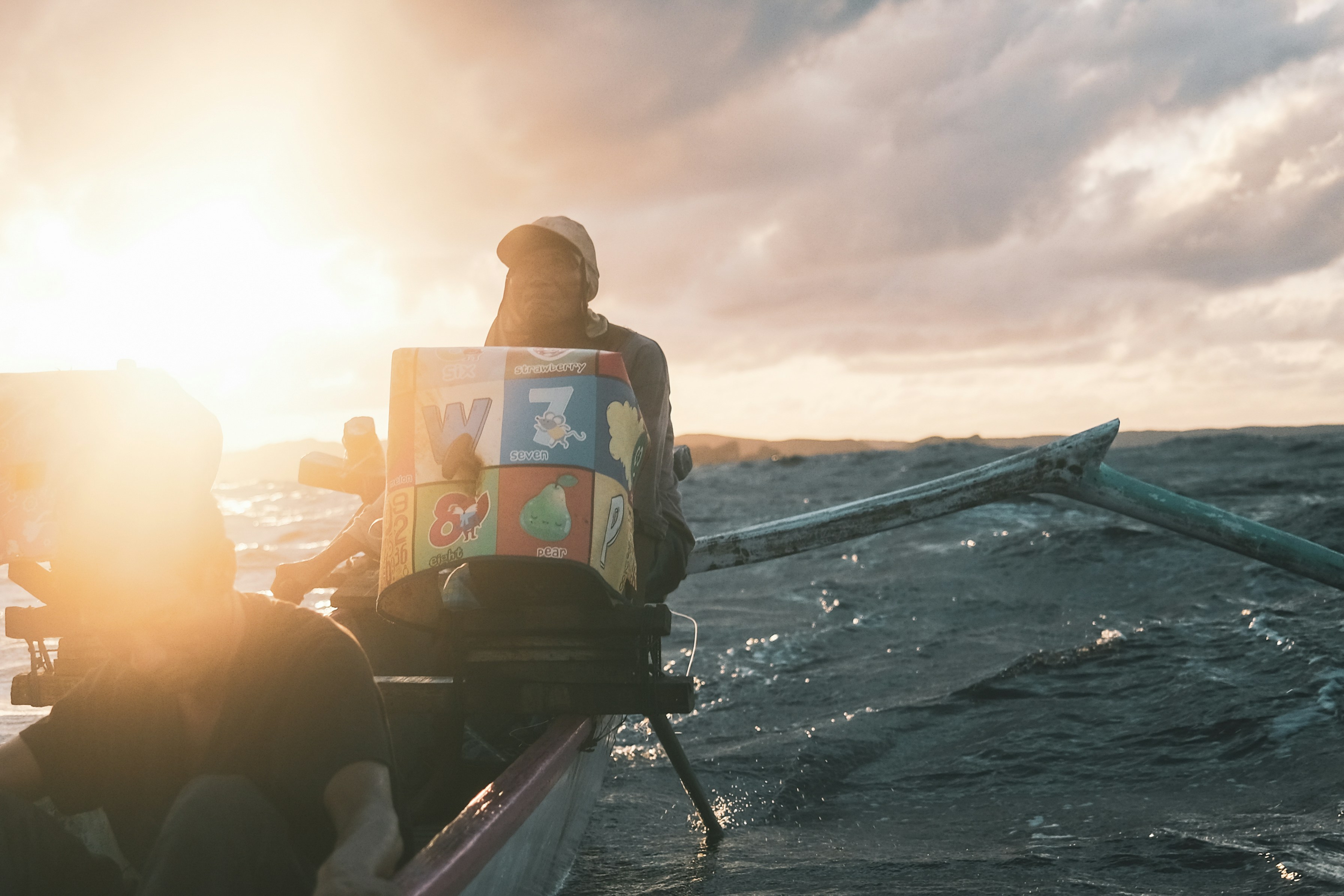 People in a boat with a box at sunset.