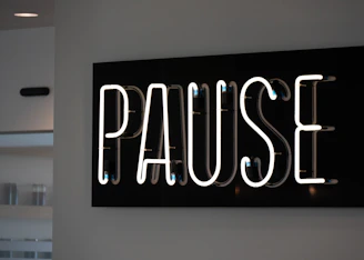 White neon sign spelling out the word pause.
