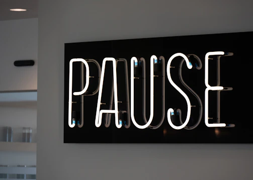 White neon sign spelling out the word pause.