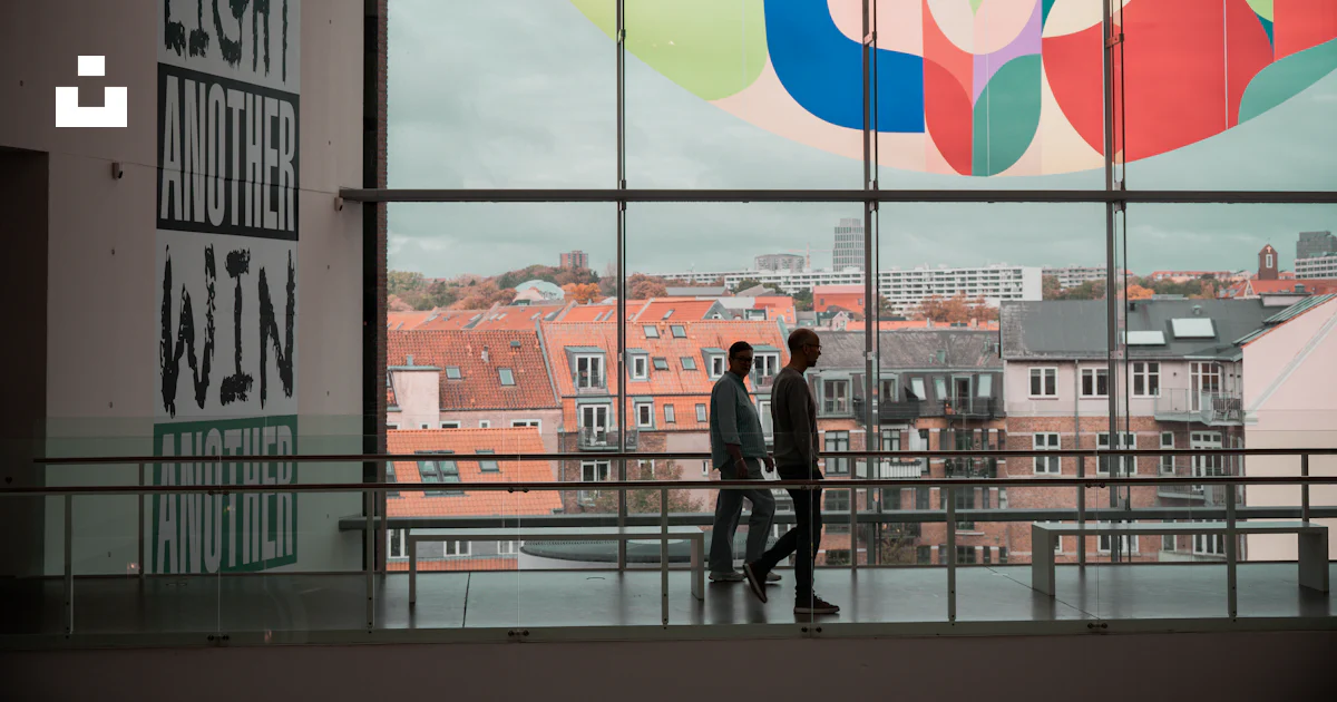 Two people walk past a large window with art. photo – Free Art Image on ...