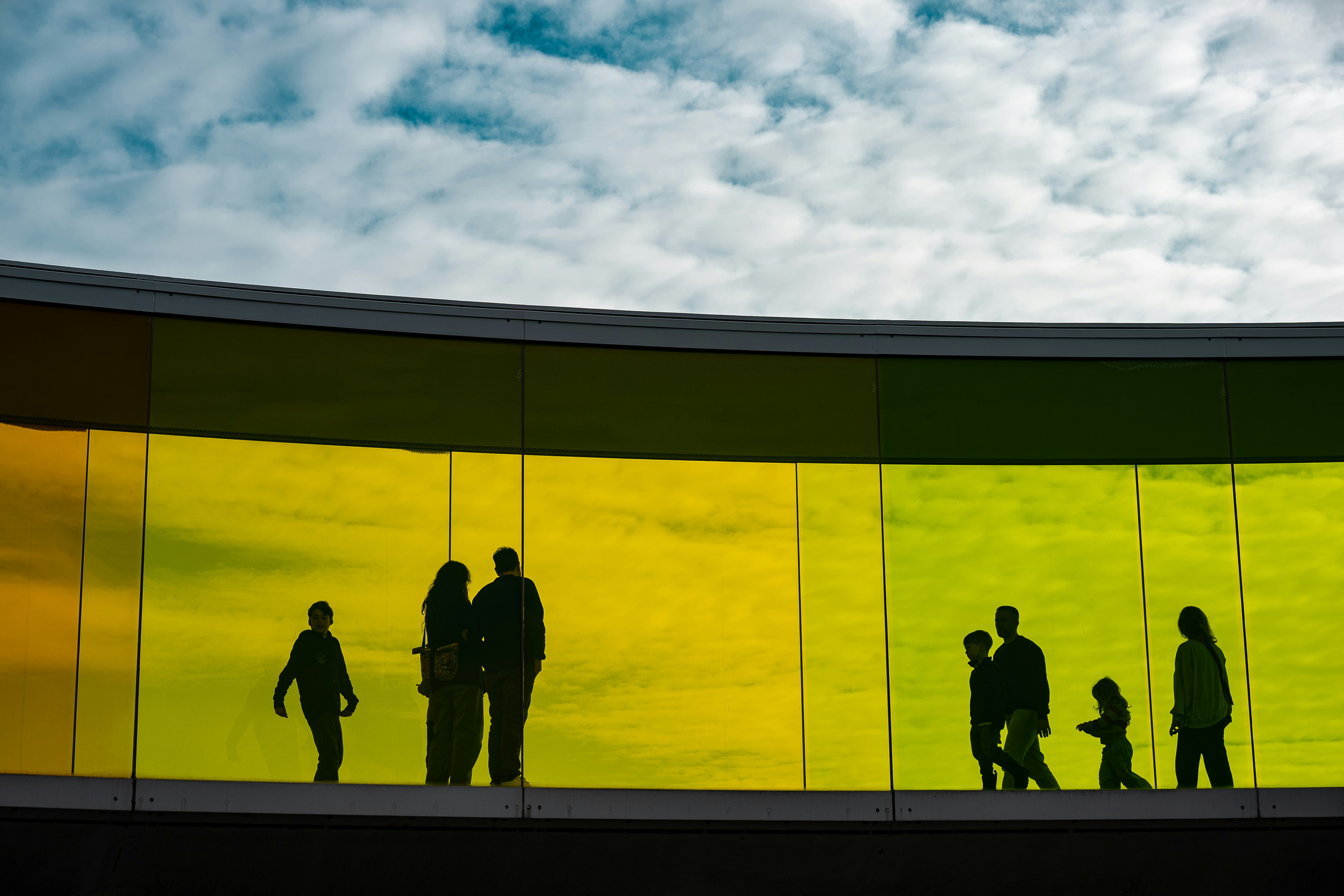 Silhouettes of people walking on a rainbow-colored walkway