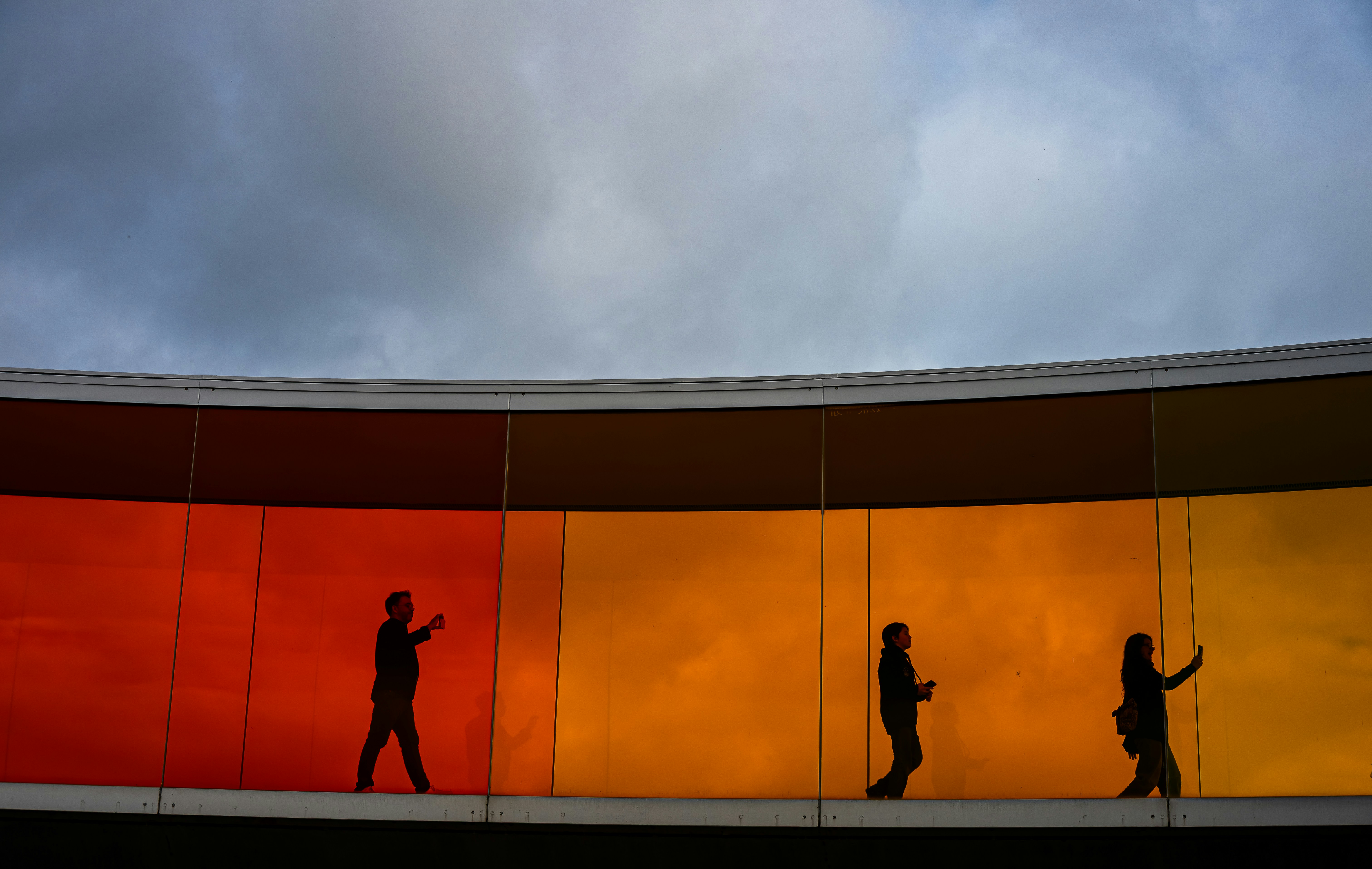 Silhouettes of people walking on a colorful walkway