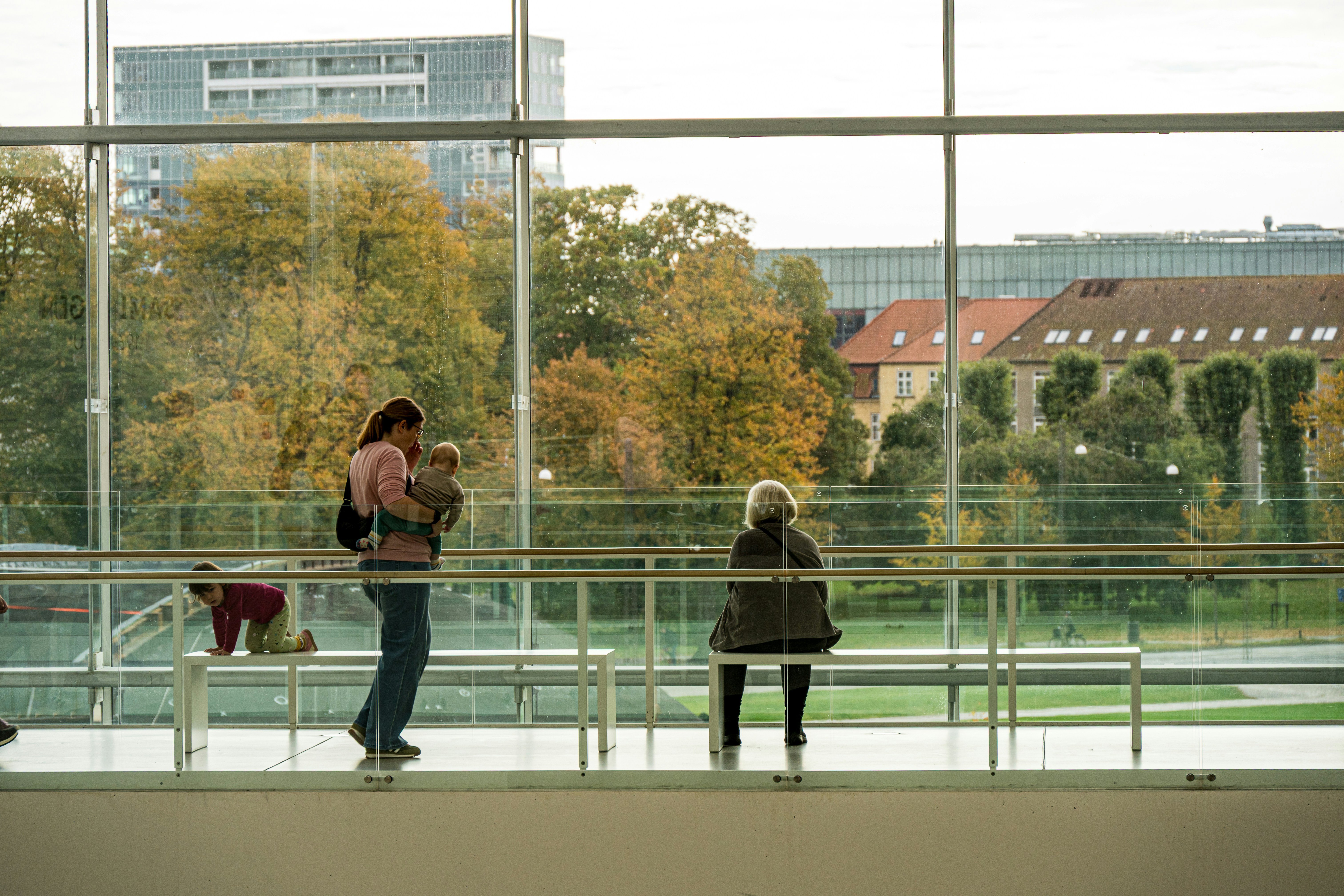 People looking out large windows at autumn trees