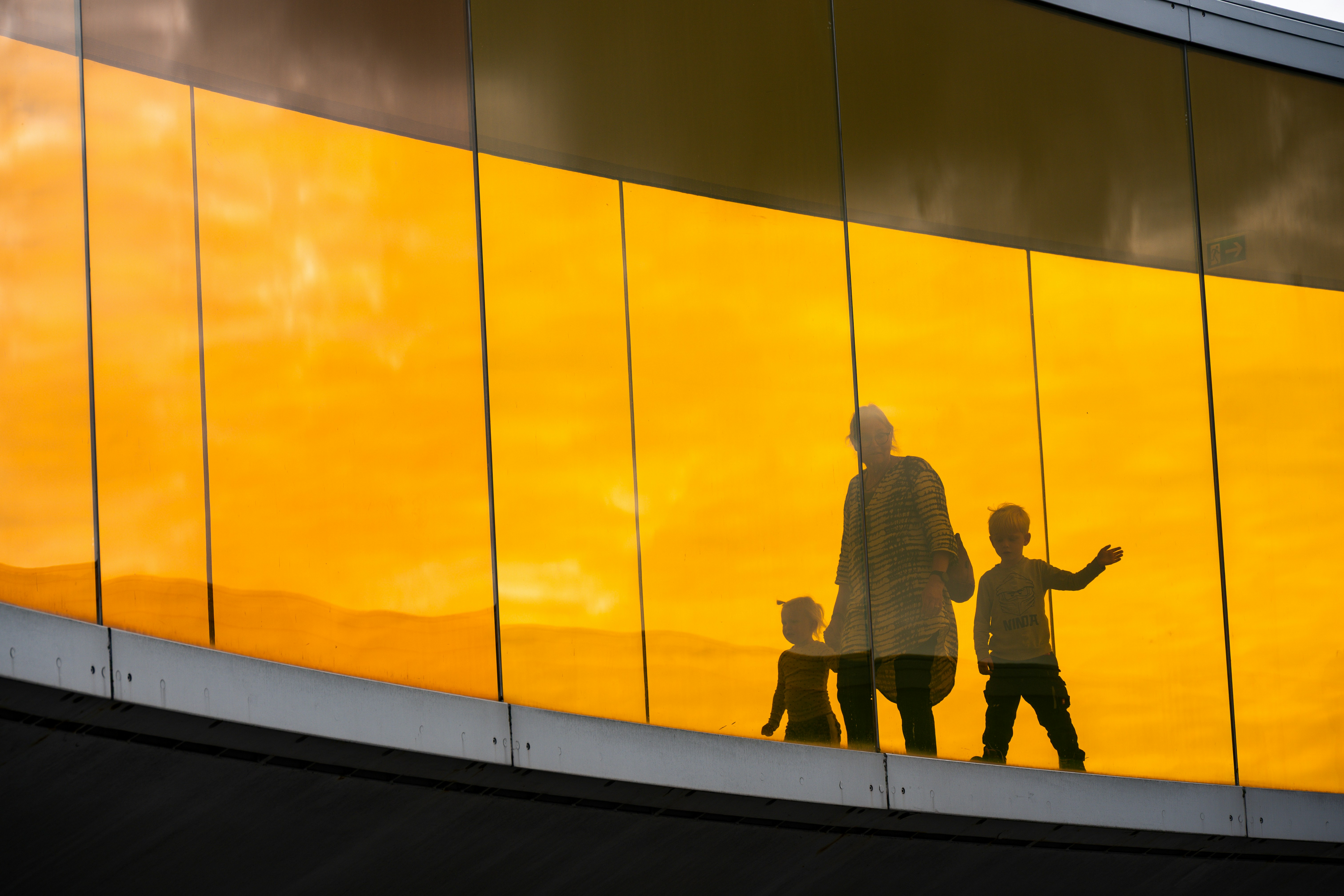 Silhouettes of people against a vibrant orange background