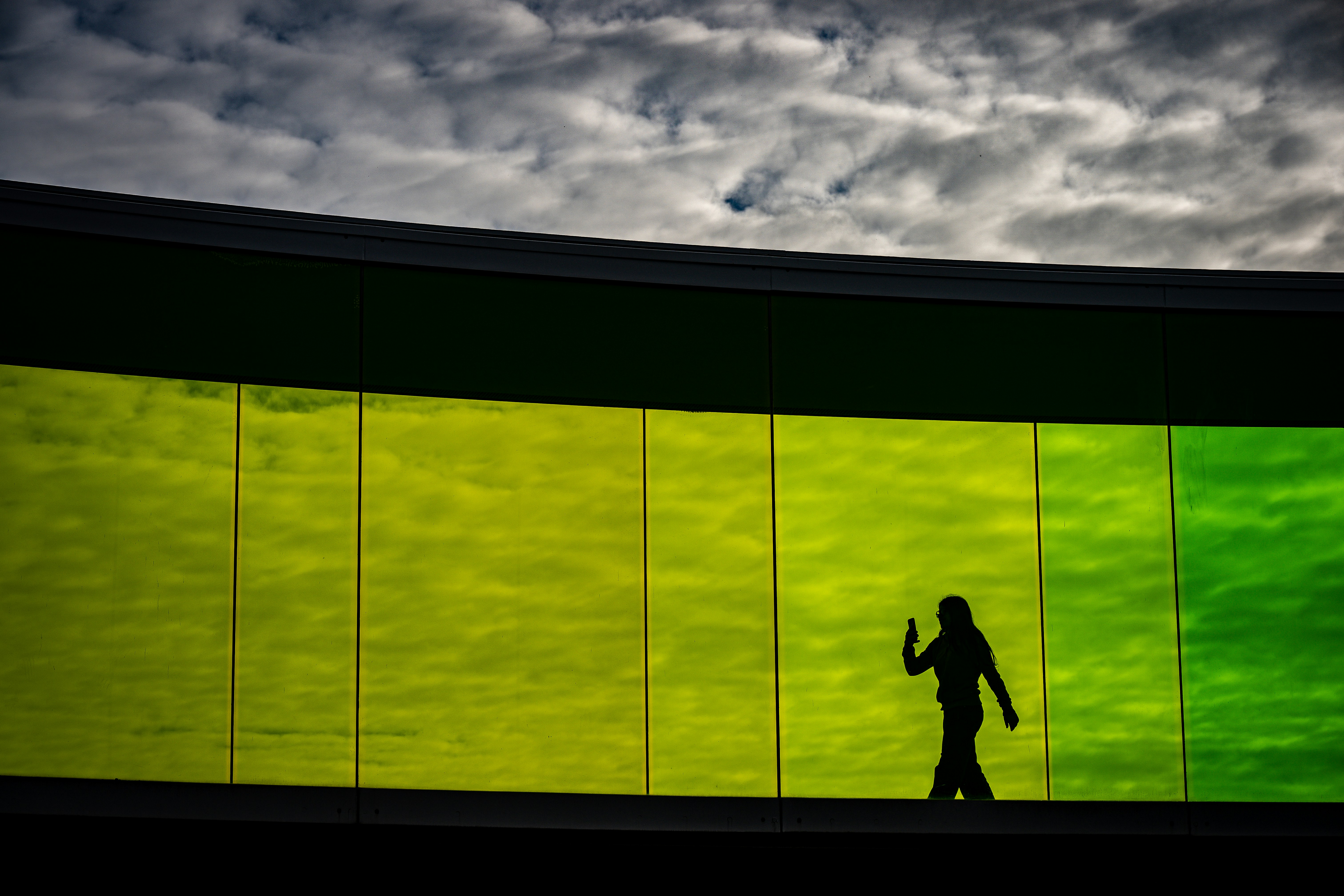 Silhouette of a person walking against a colorful wall