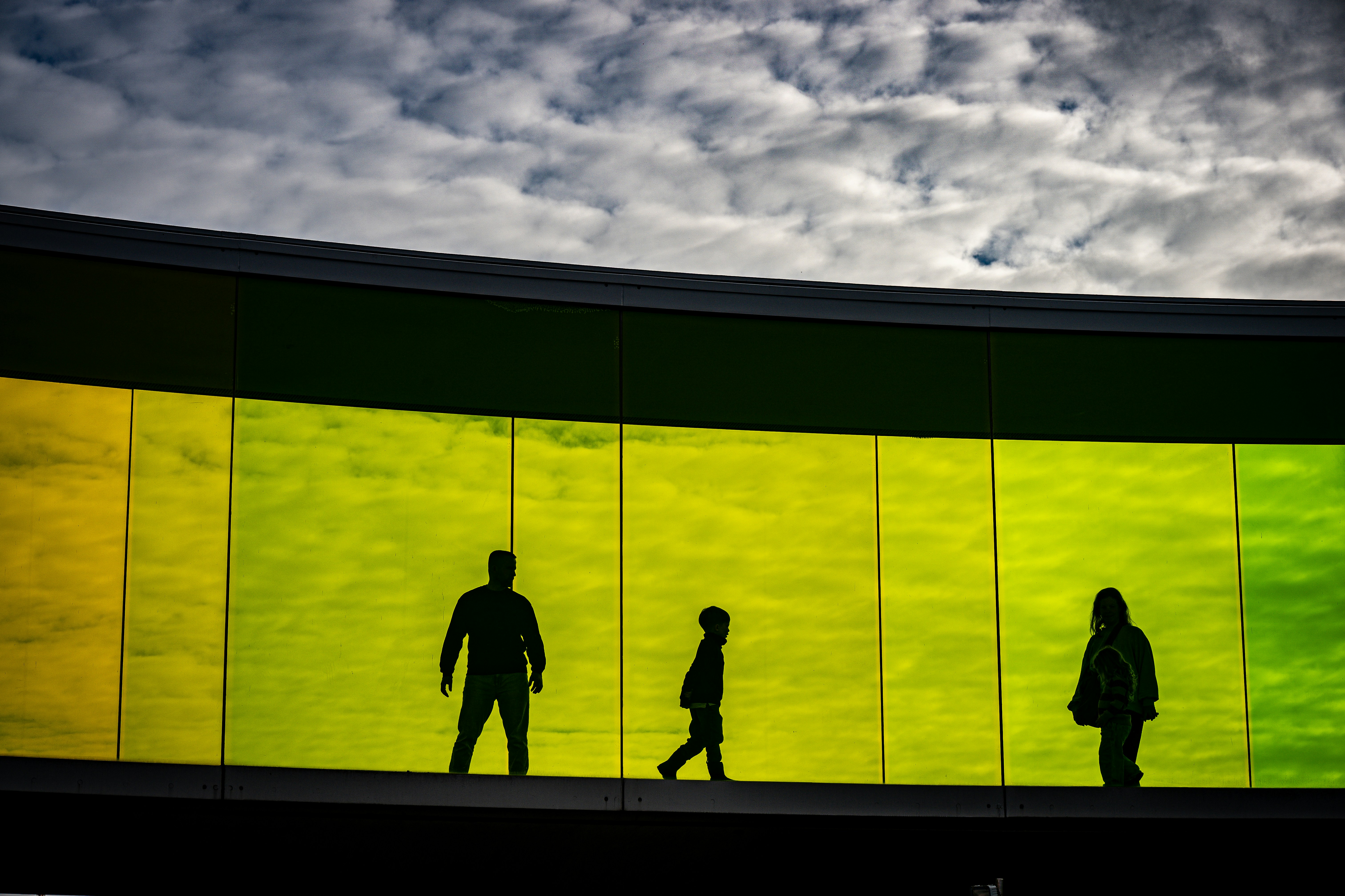 Silhouettes of people against a colorful rainbow wall.