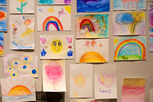 Collection of colorful children's drawings on a wall.