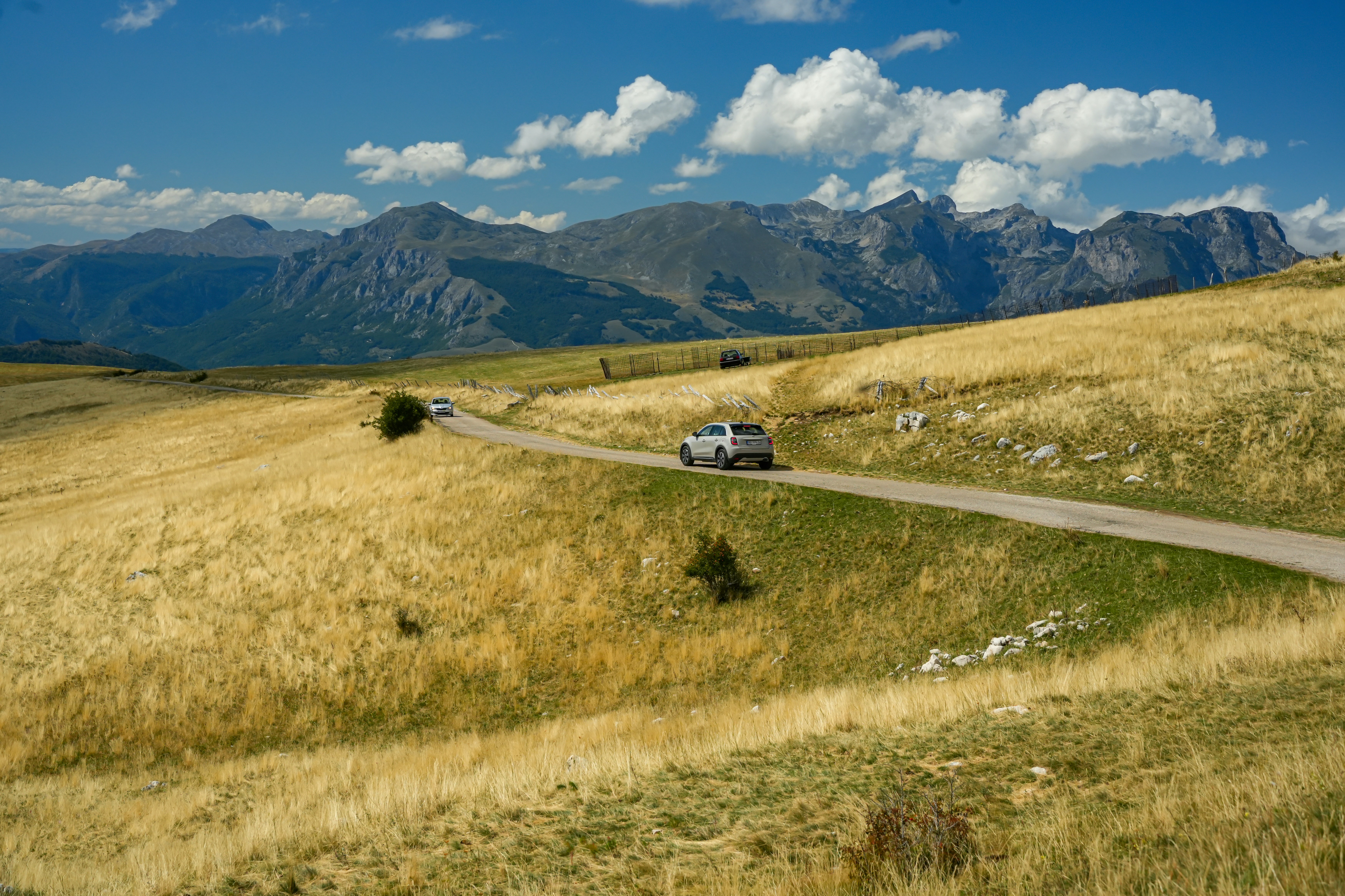 Car driving on a road through golden hills