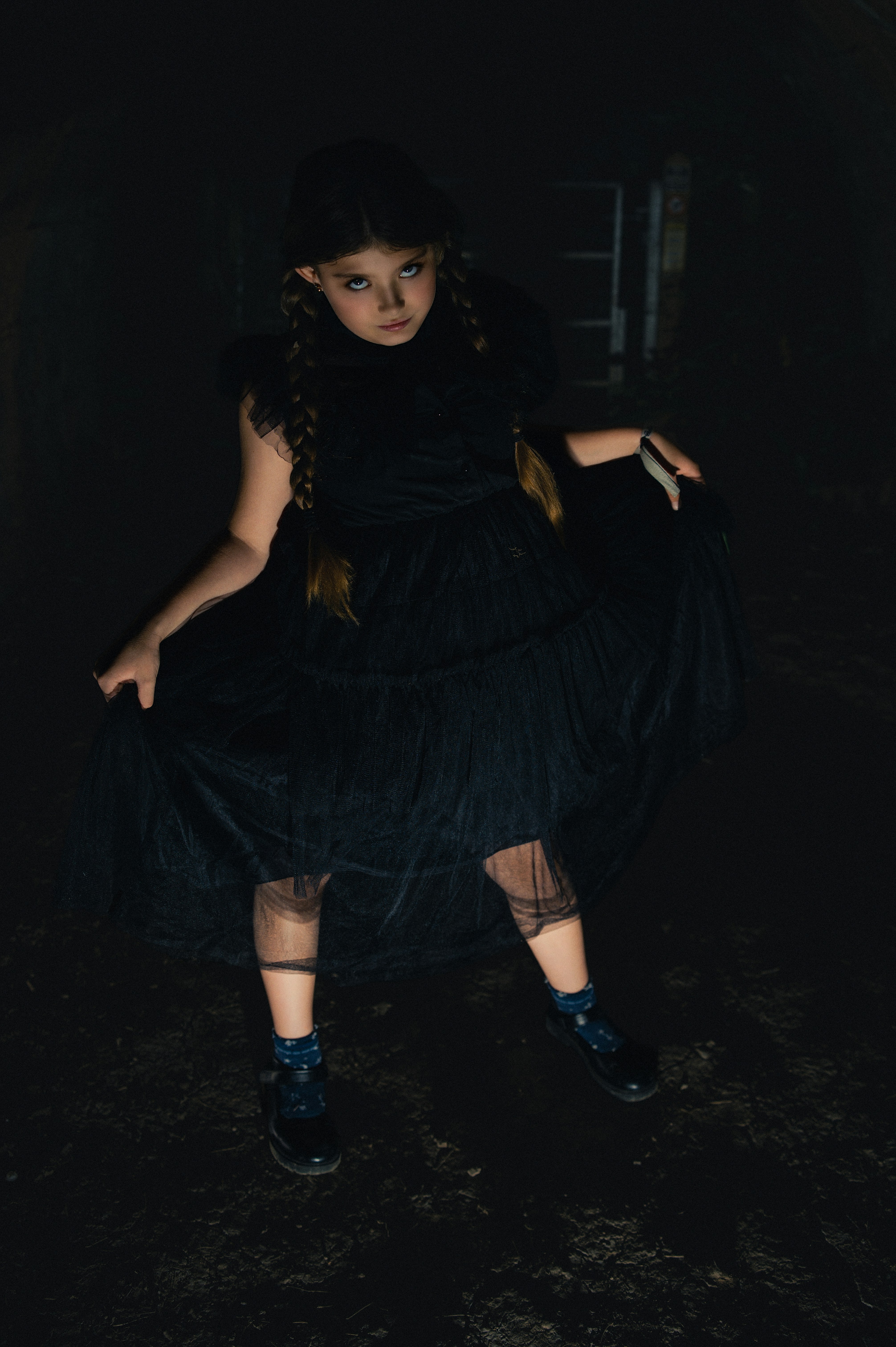 A young girl in a black dress with pigtails.