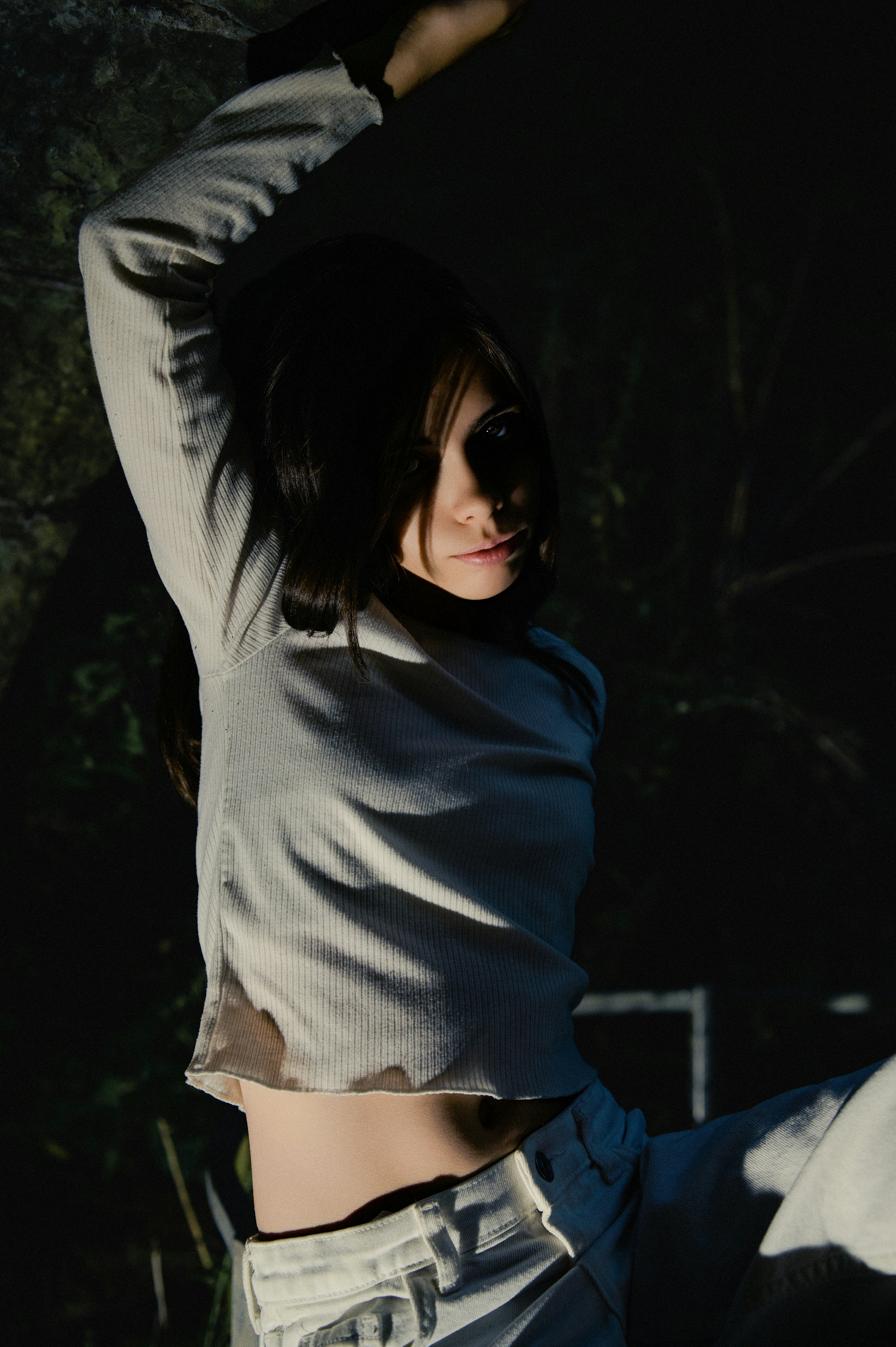 Young woman with arms raised in dramatic lighting