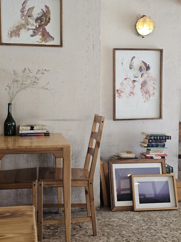 Artistic portraits hang above a wooden table and chairs.