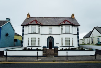 A white two-story house with a dark roof.