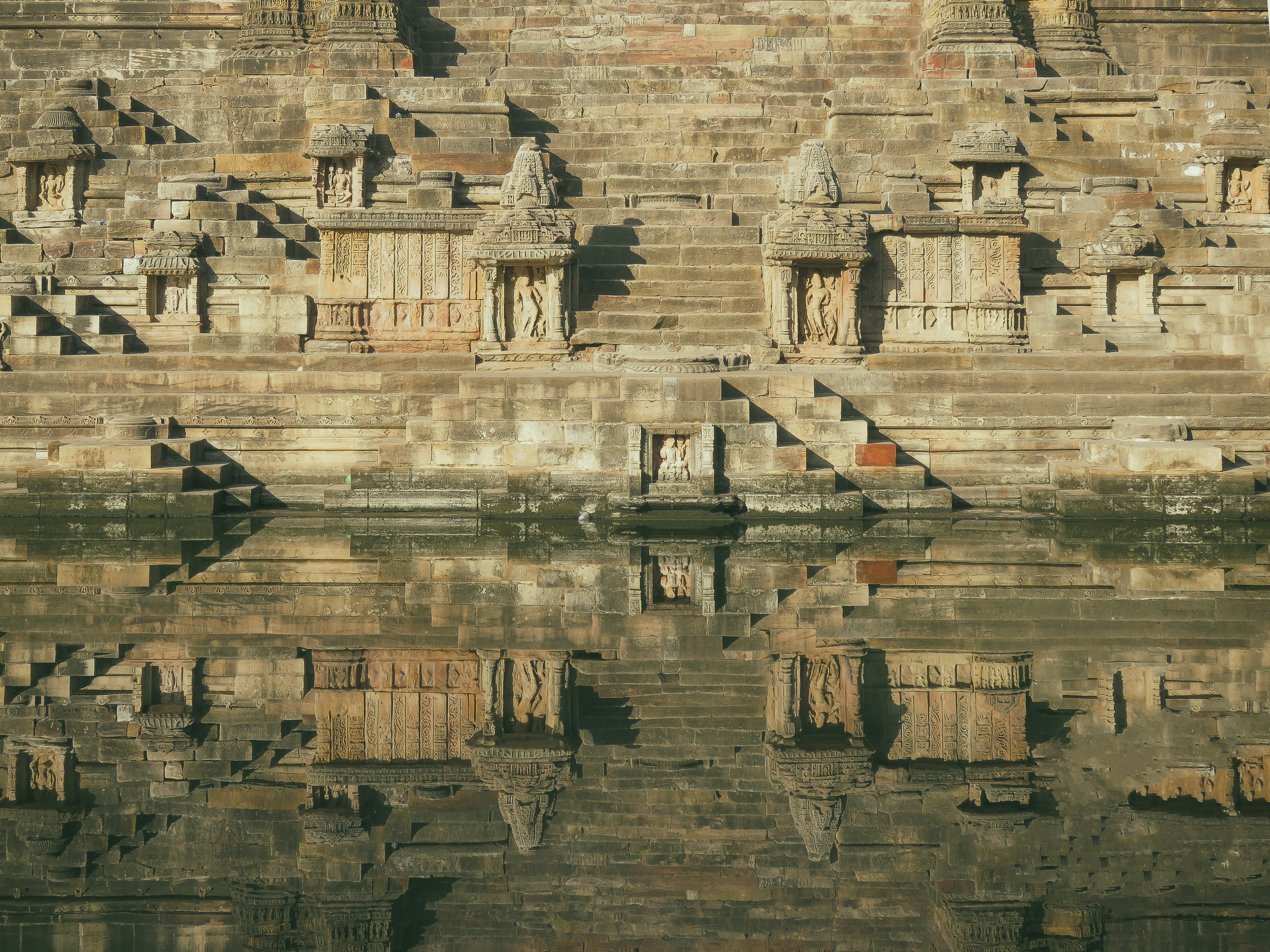 Ancient stone steps and structures reflected in water.
