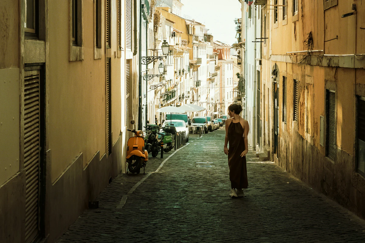 Woman walking down narrow european street with scooters.