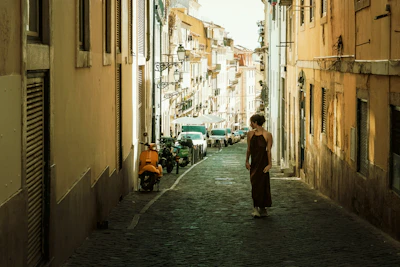 Woman walking down narrow european street with scooters.