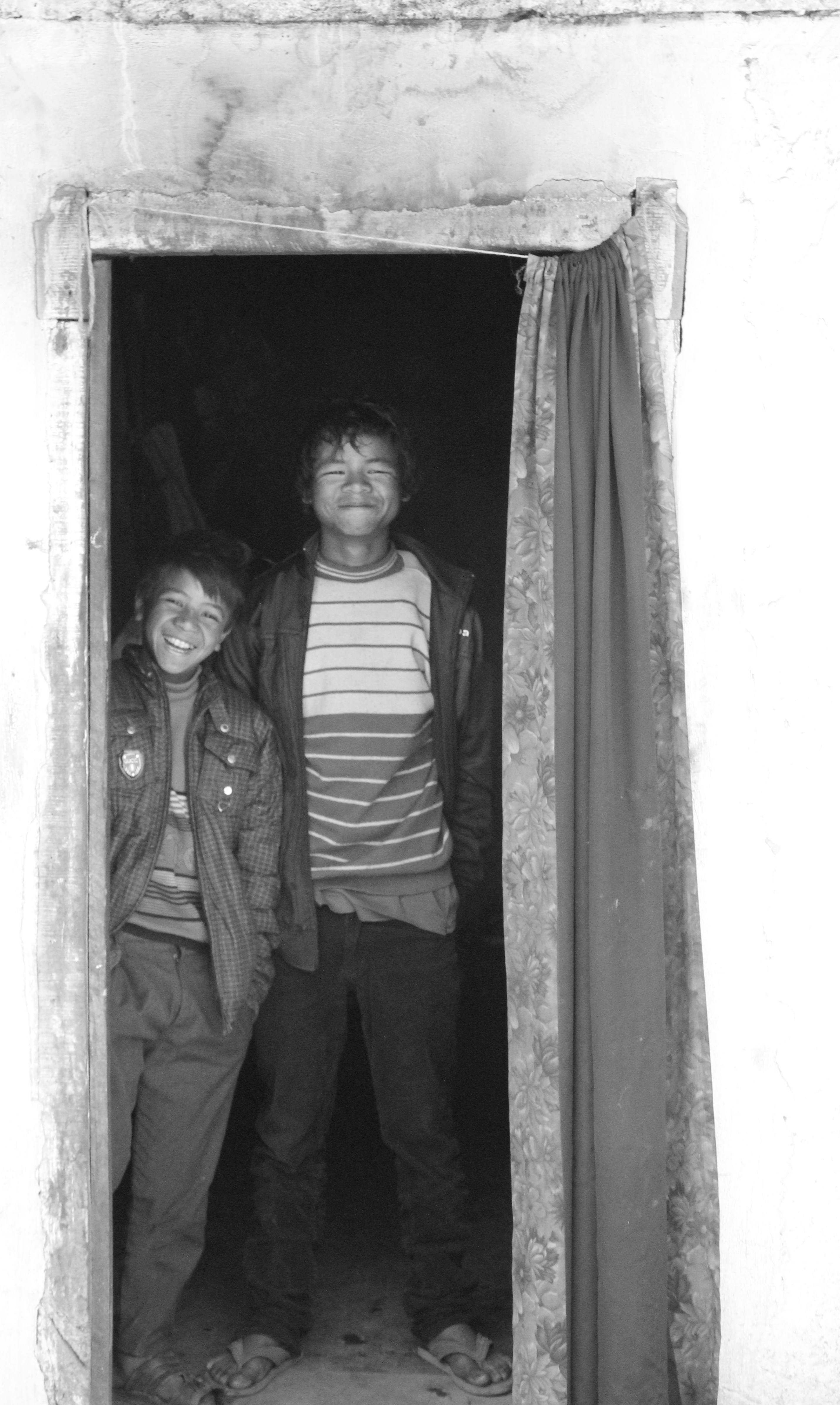 Two boys stand in a doorway, smiling.