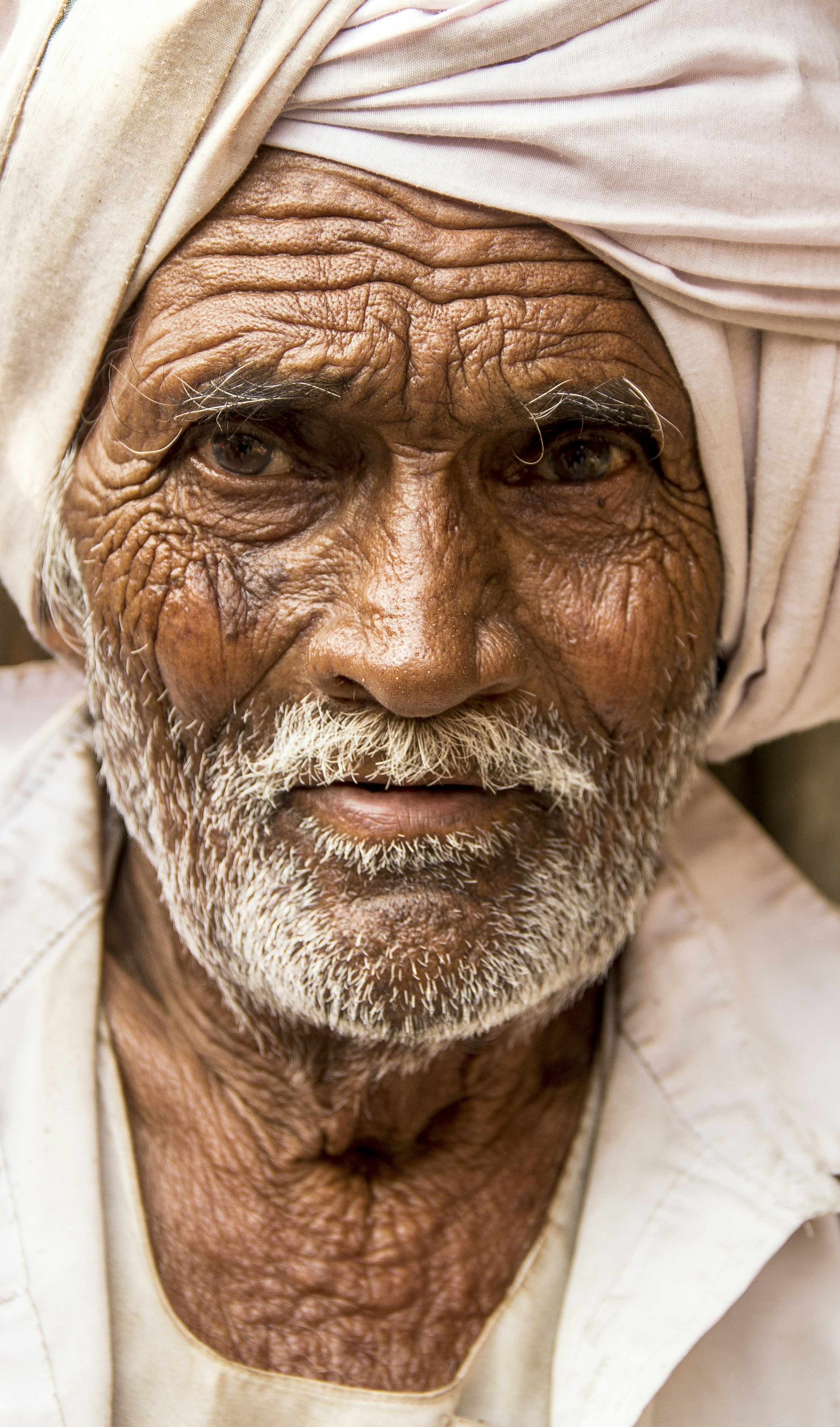 Elderly man with weathered skin and white turban.