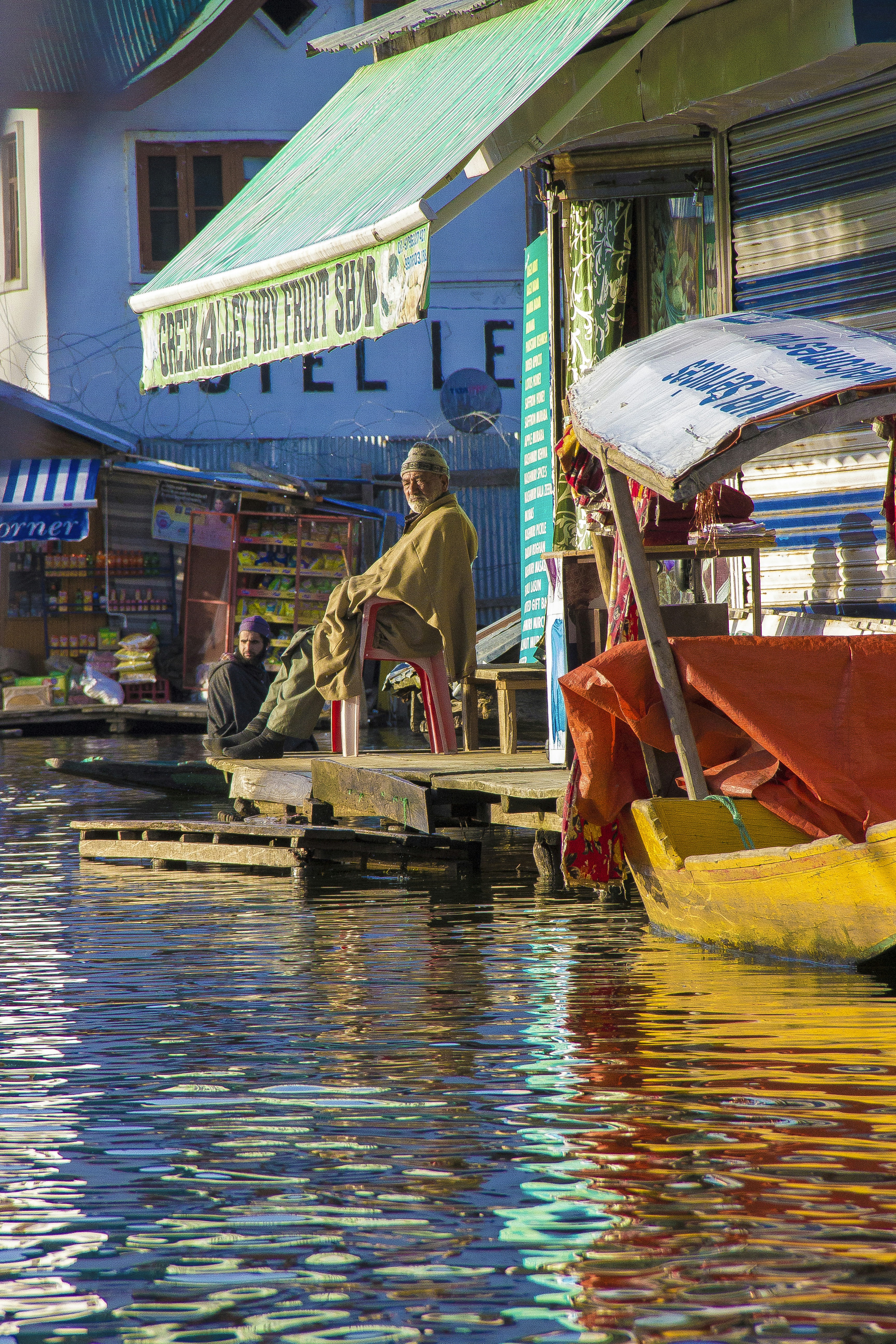 People sitting by a floating market on a canal.