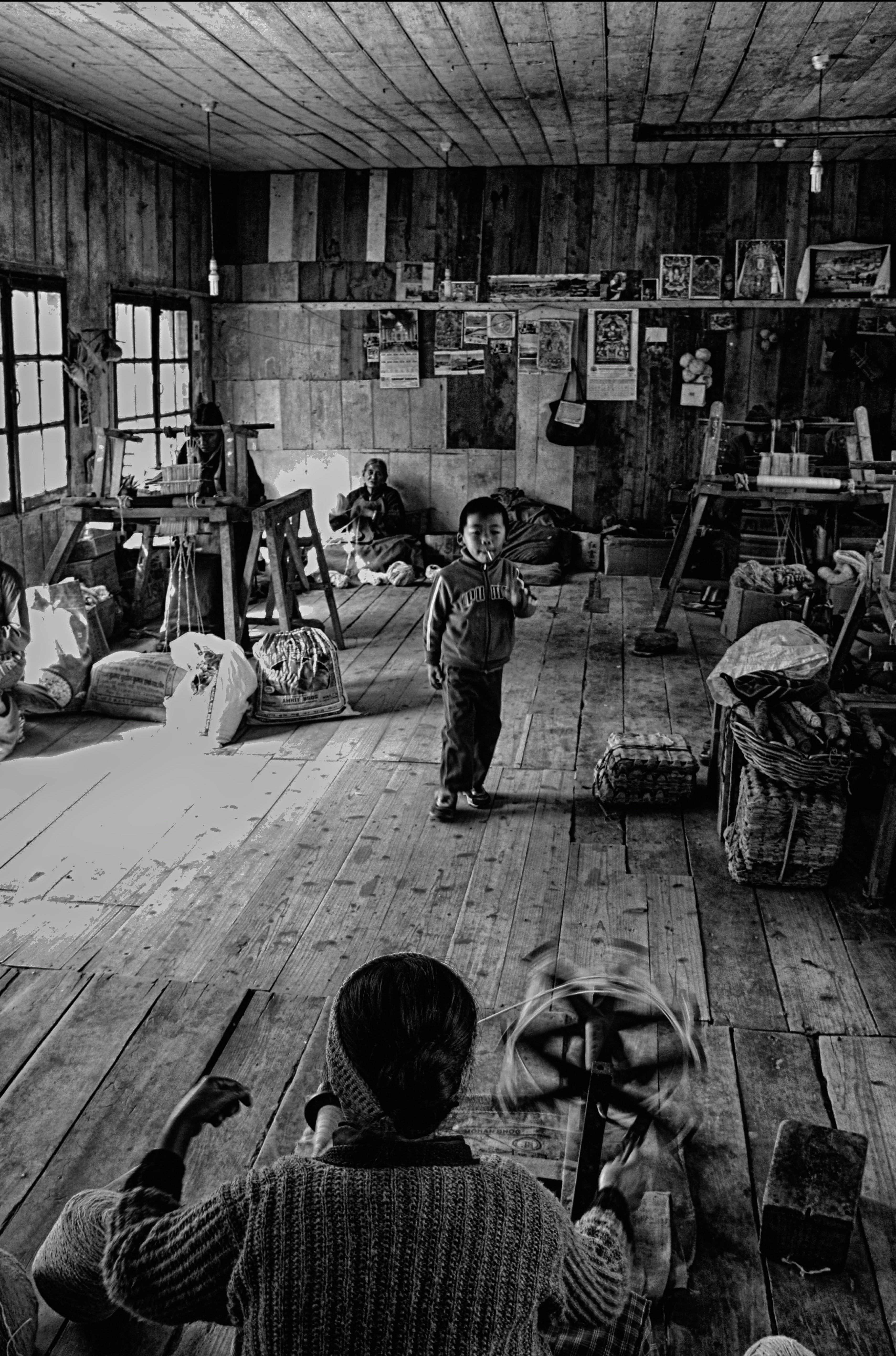 Child stands in rustic room with people working