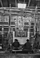Two people weaving a rug on a loom