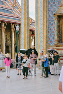 Tourists visit a temple with ornate golden columns
