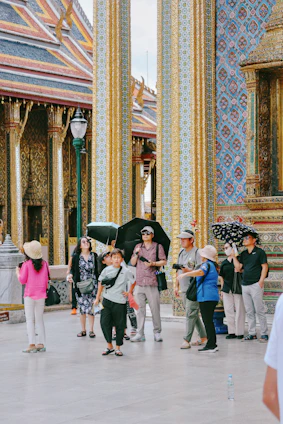 Tourists visit a temple with ornate golden columns