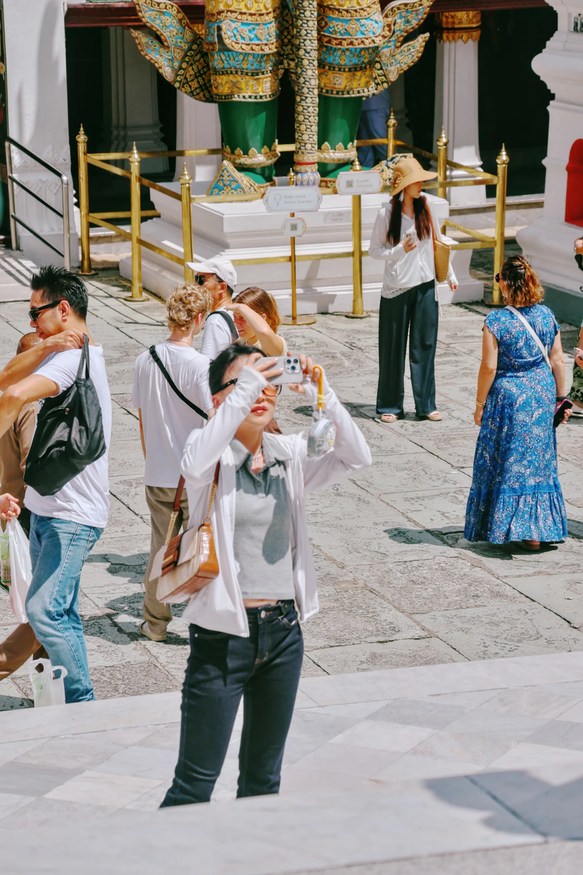 Visitors among guardian statues and ornate architecture at Bangkok's Grand Palace