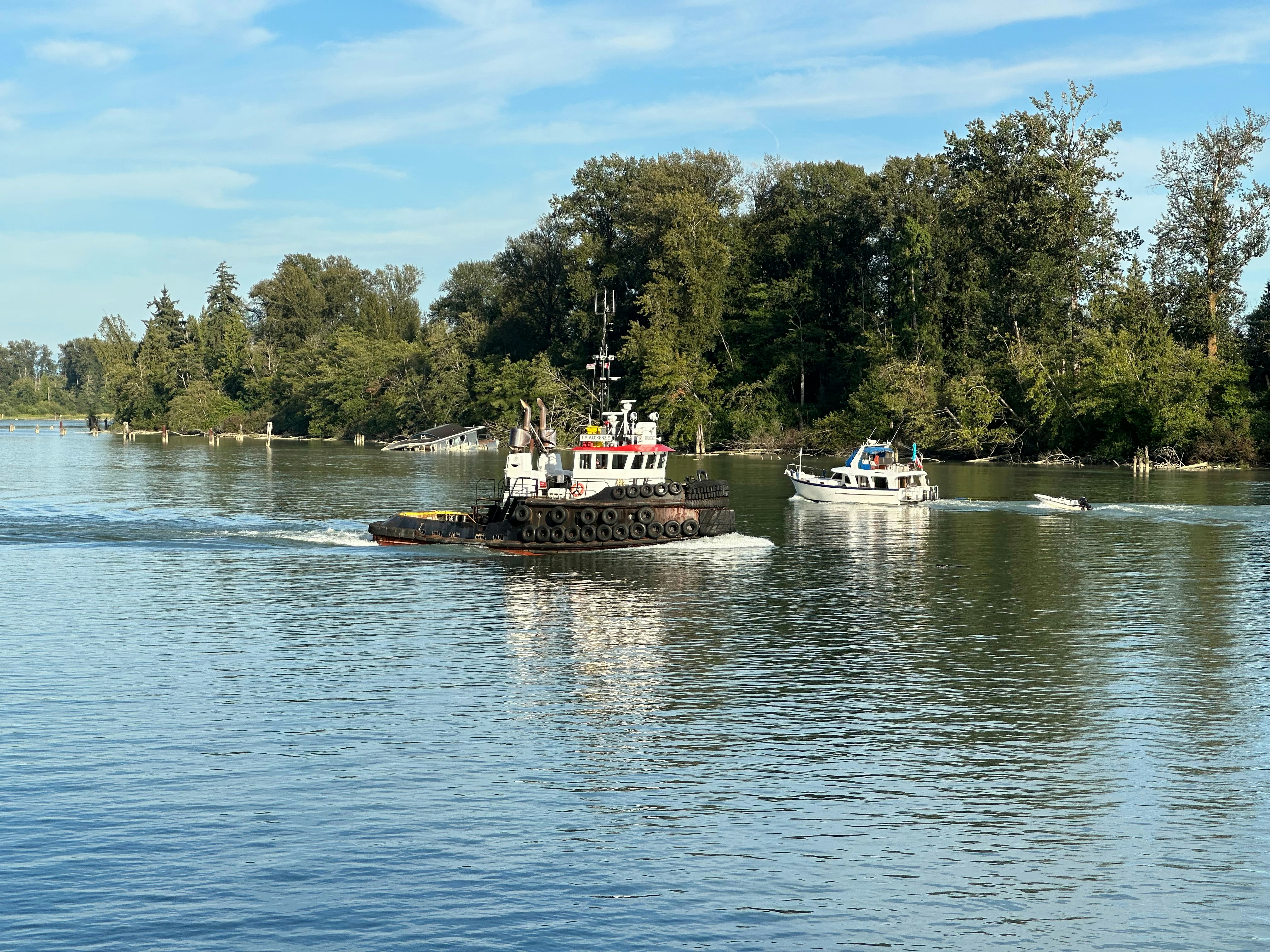 Two boats traveling on a wide, calm river.