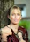 Blonde woman with blue eyes leaning against tree