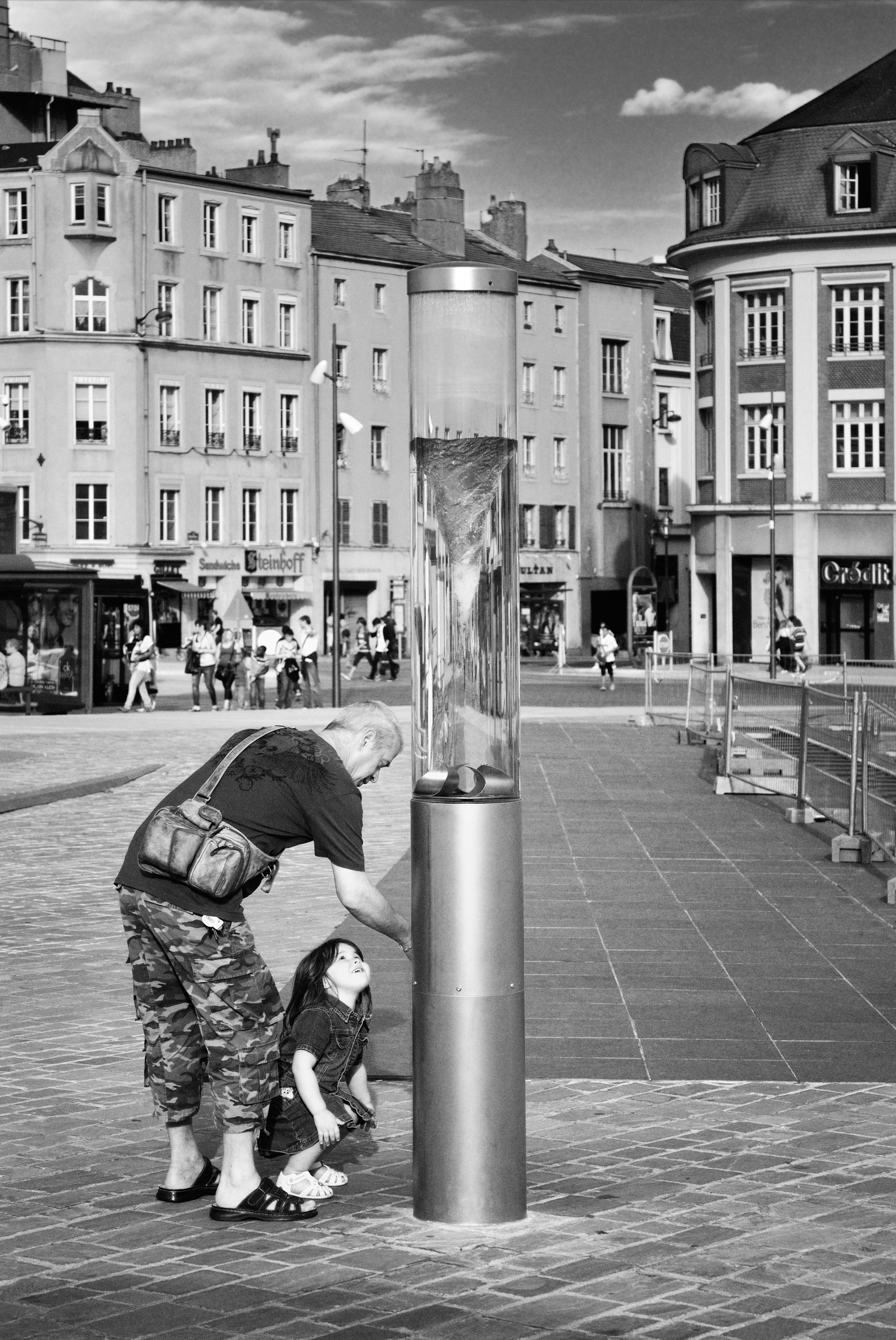 Man and child interact with a modern sculpture.
