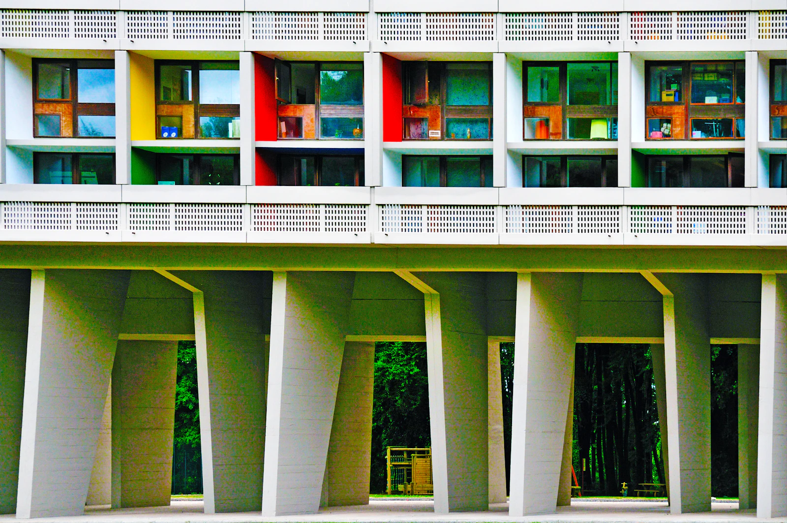 Modern building facade with colourful windows and open concrete structure.