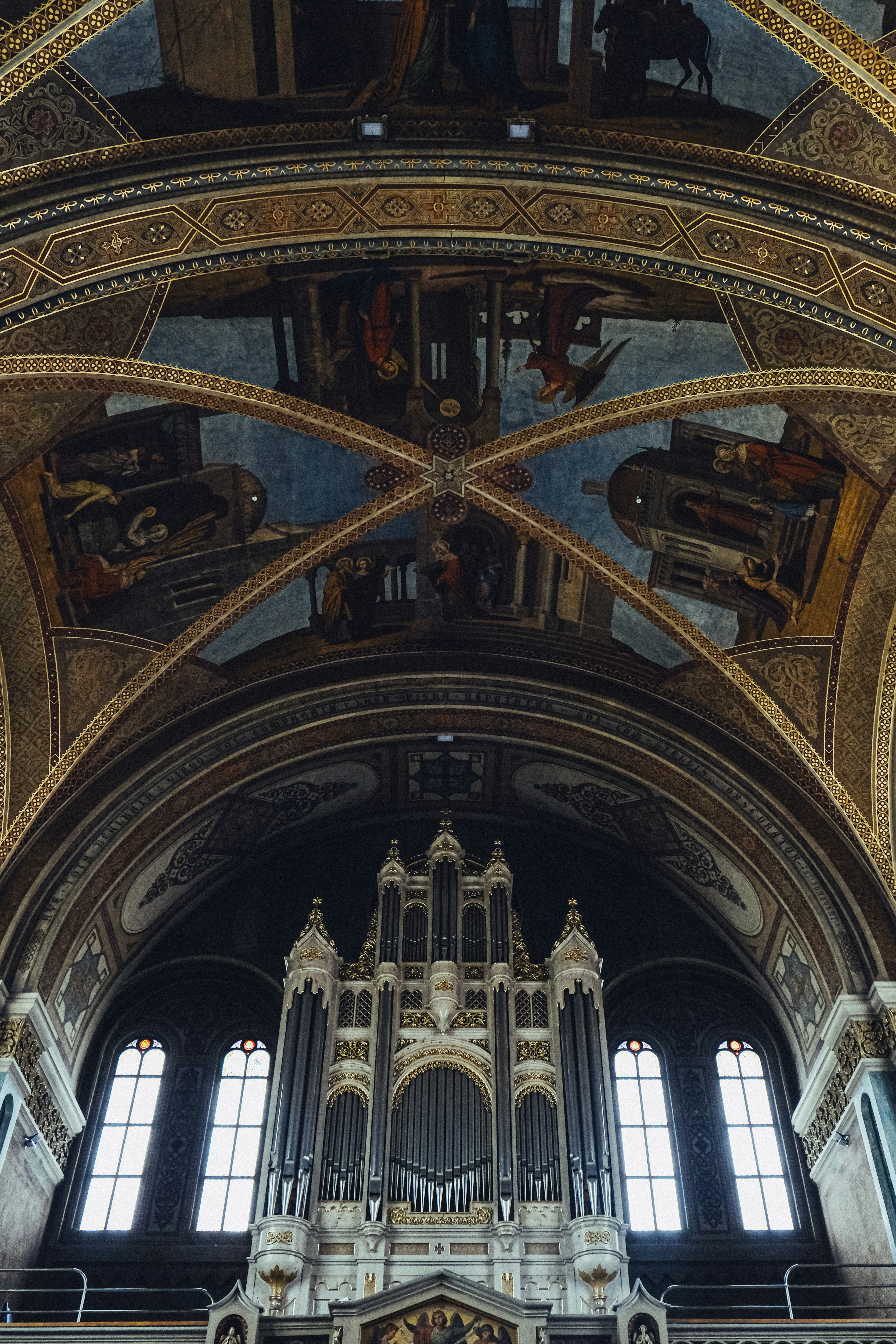 Ornate pipe organ beneath a painted church ceiling