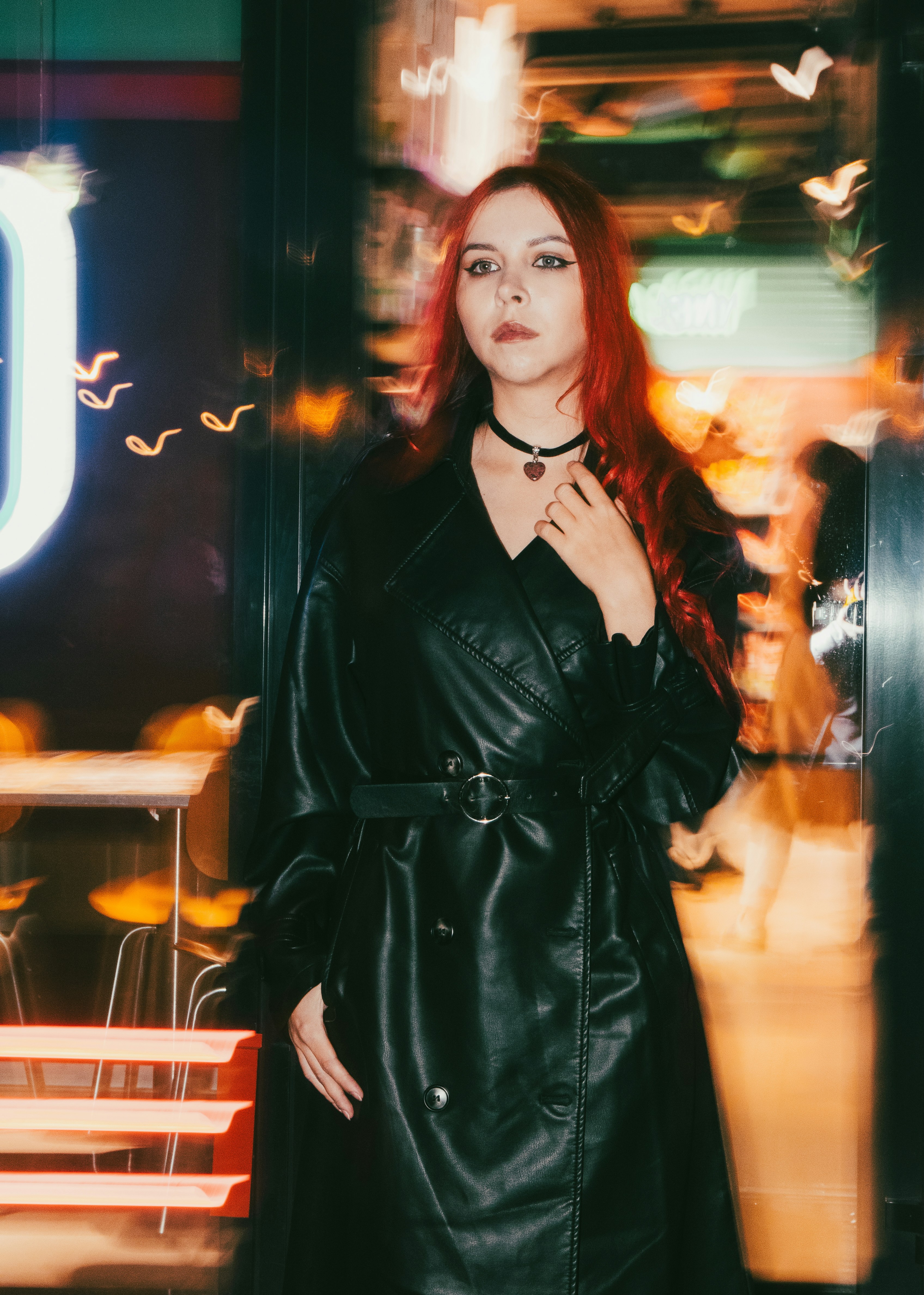 Woman in black coat with red hair at night