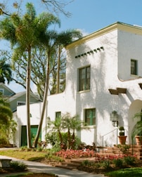White stucco house with palm trees and garden.