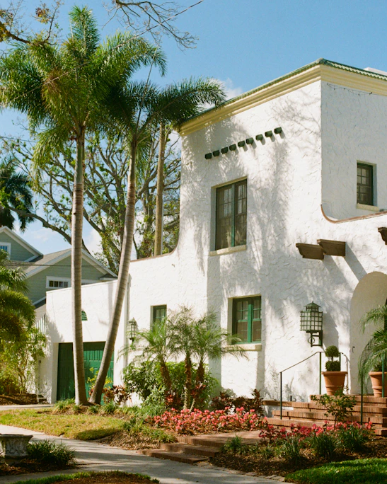 White stucco house with palm trees and garden.