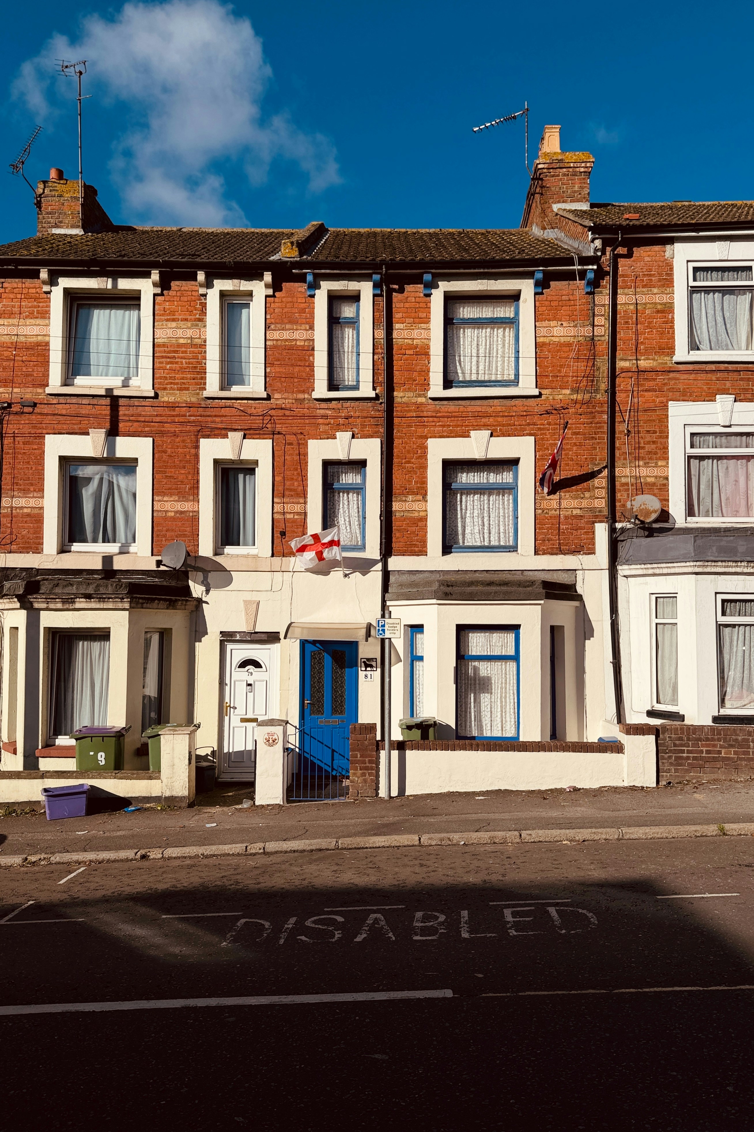 Terraced houses with blue doors under a bright sky.