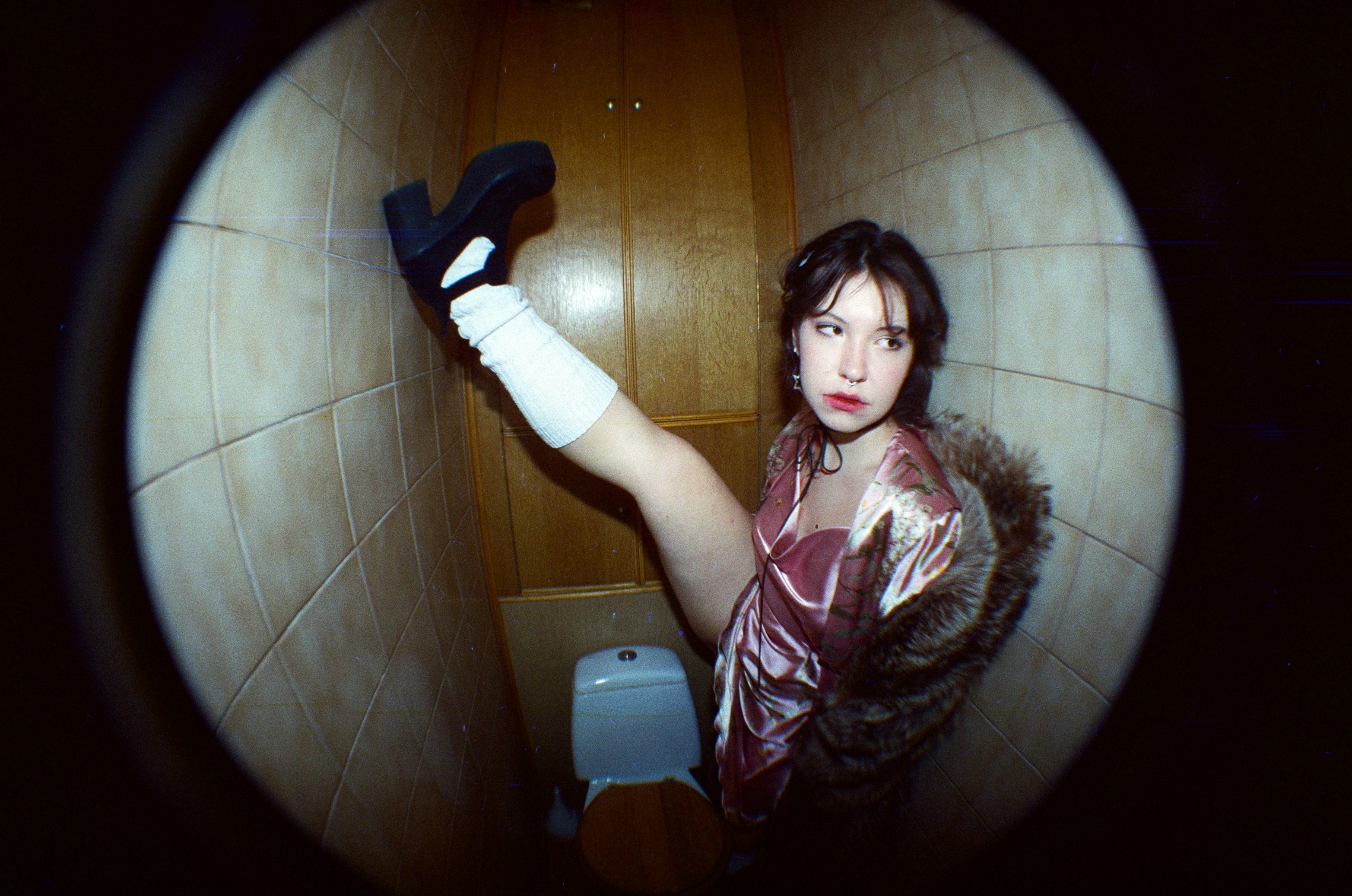 Young woman sitting on toilet in tiled room