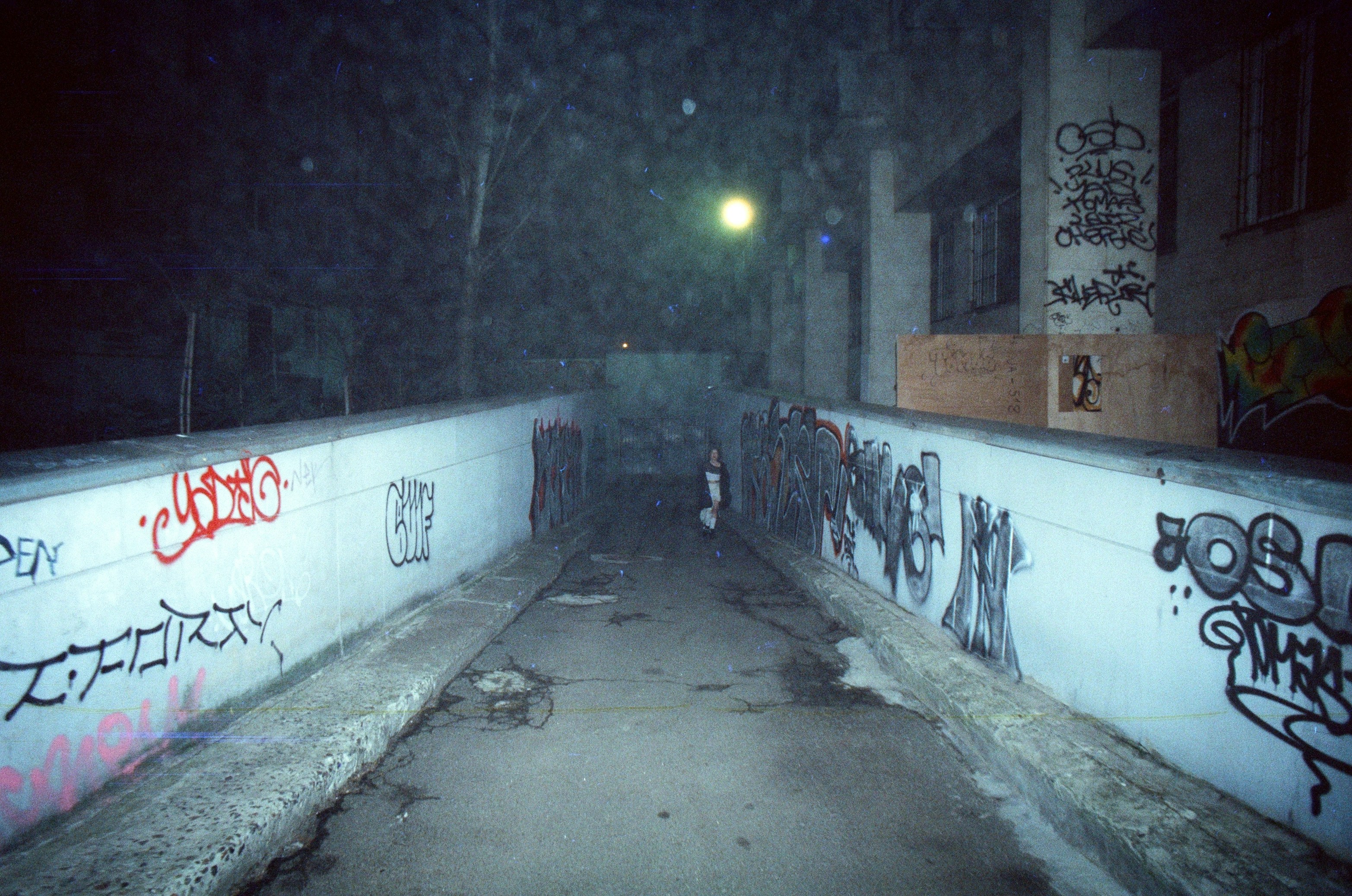 Graffiti-bedeckter Gehweg bei Nacht mit Licht über dem Kopf