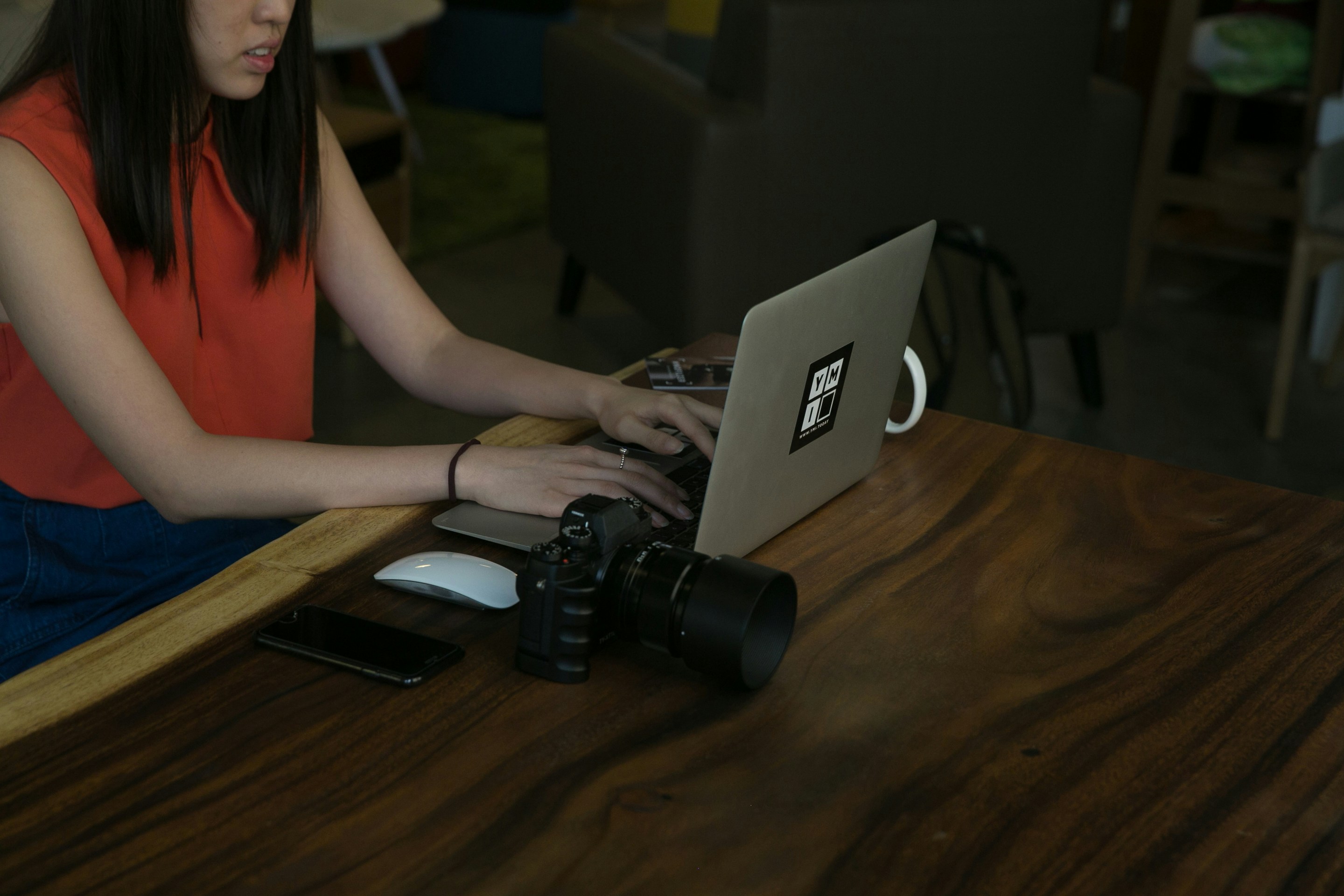 hands typing on modern laptop keyboard on wooden desk near camera lens