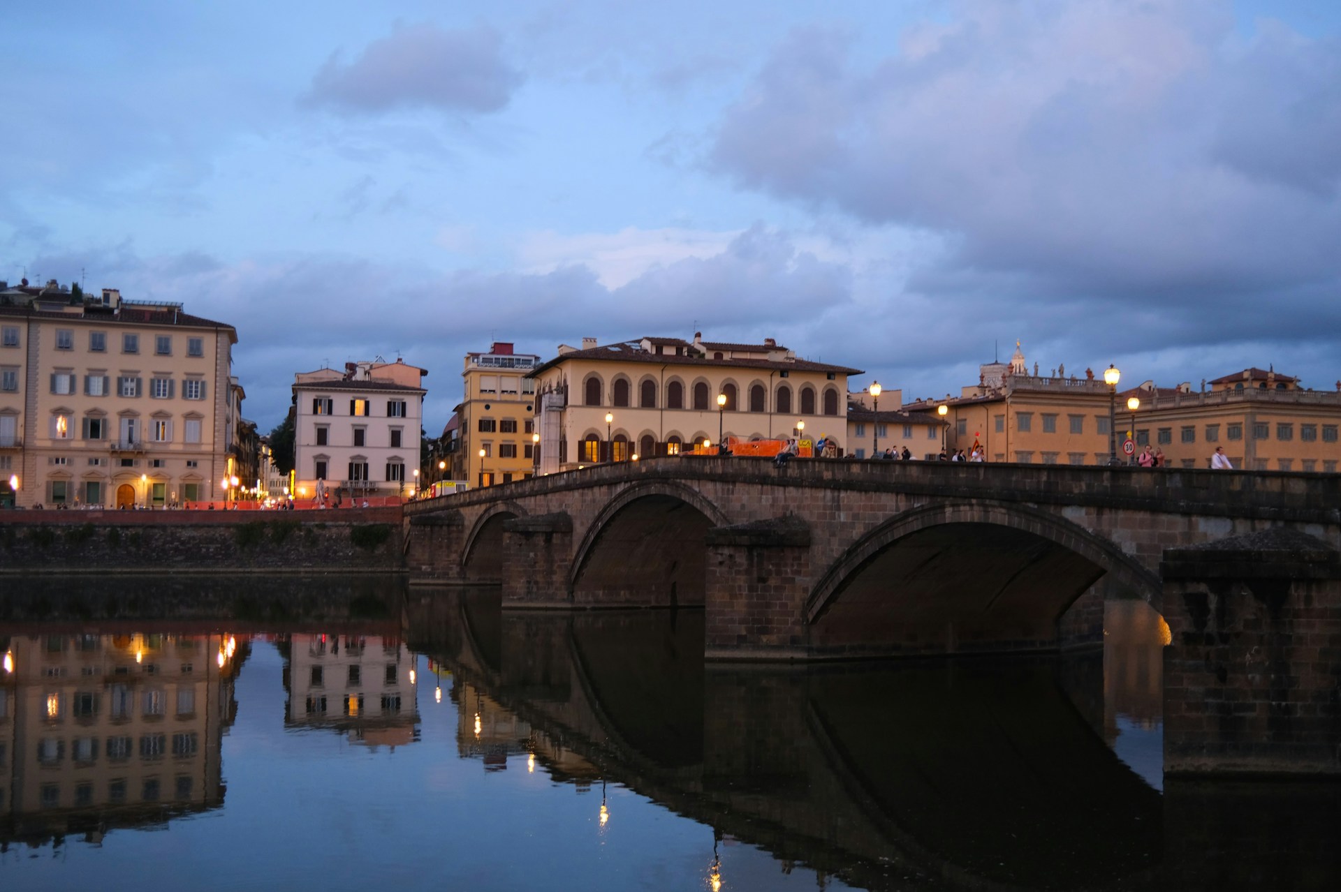 Bridge over river with buildings at dusk.