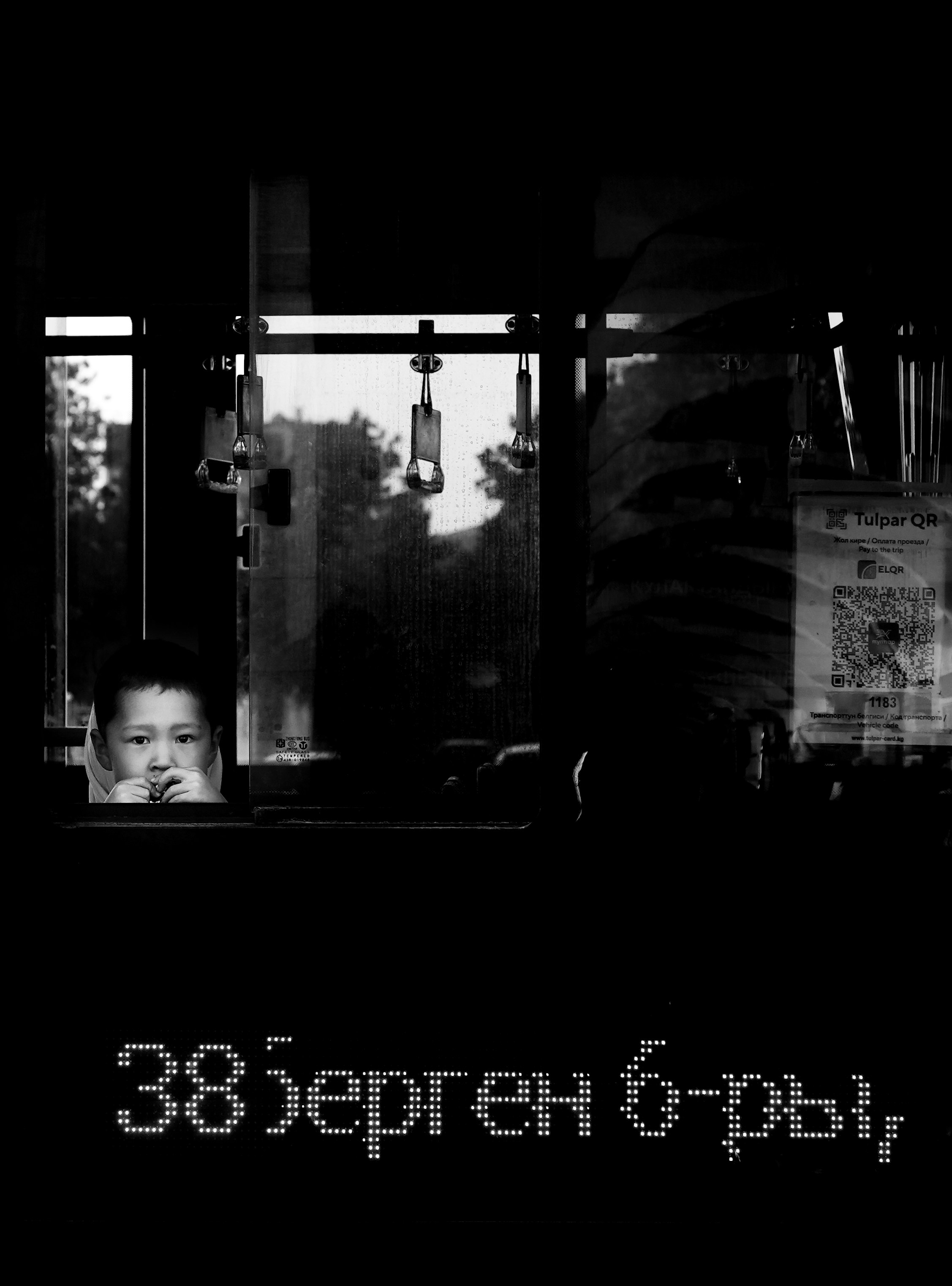 Child looking out window on bus at night.