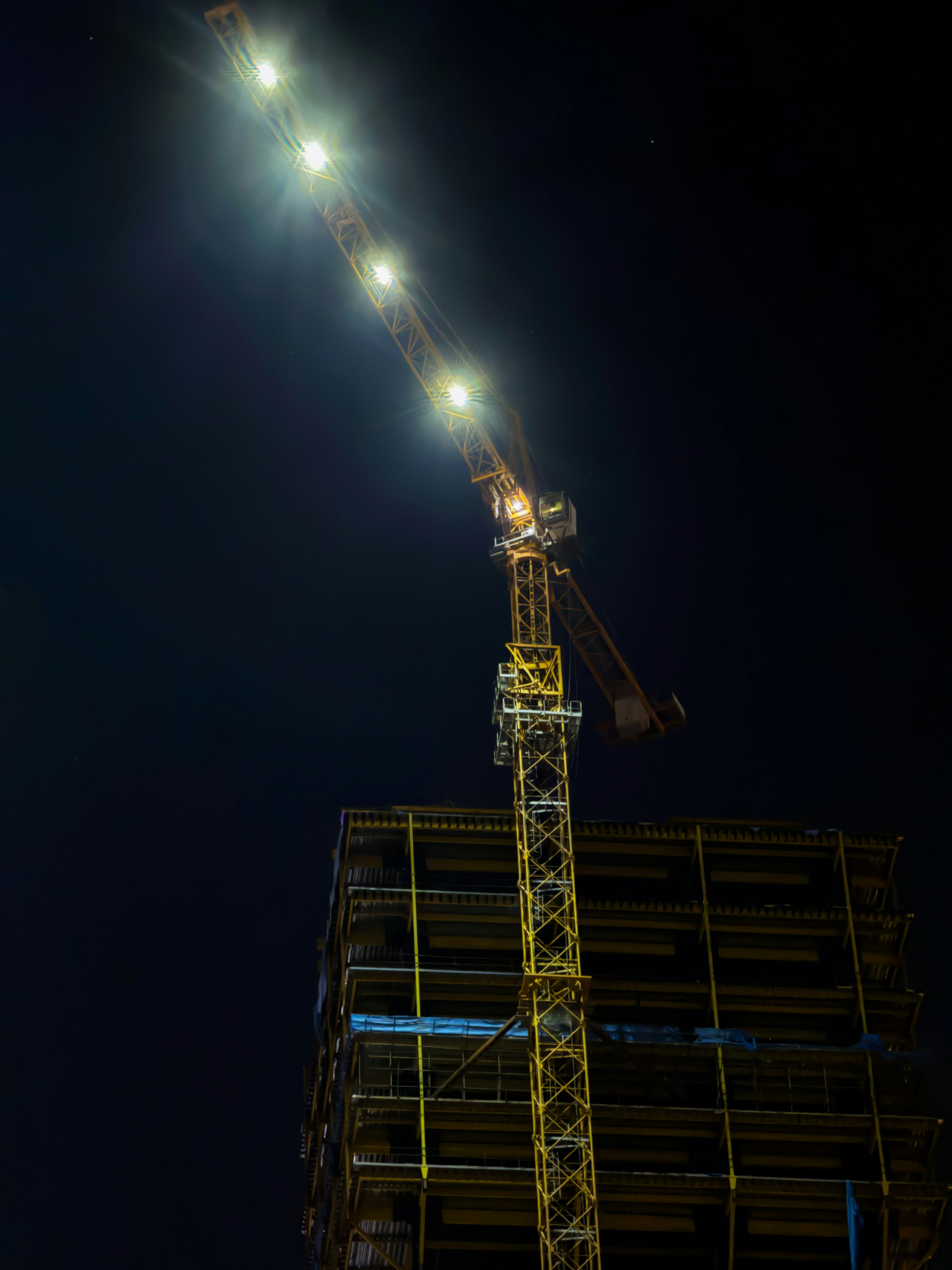 Construction crane illuminated at night over building.