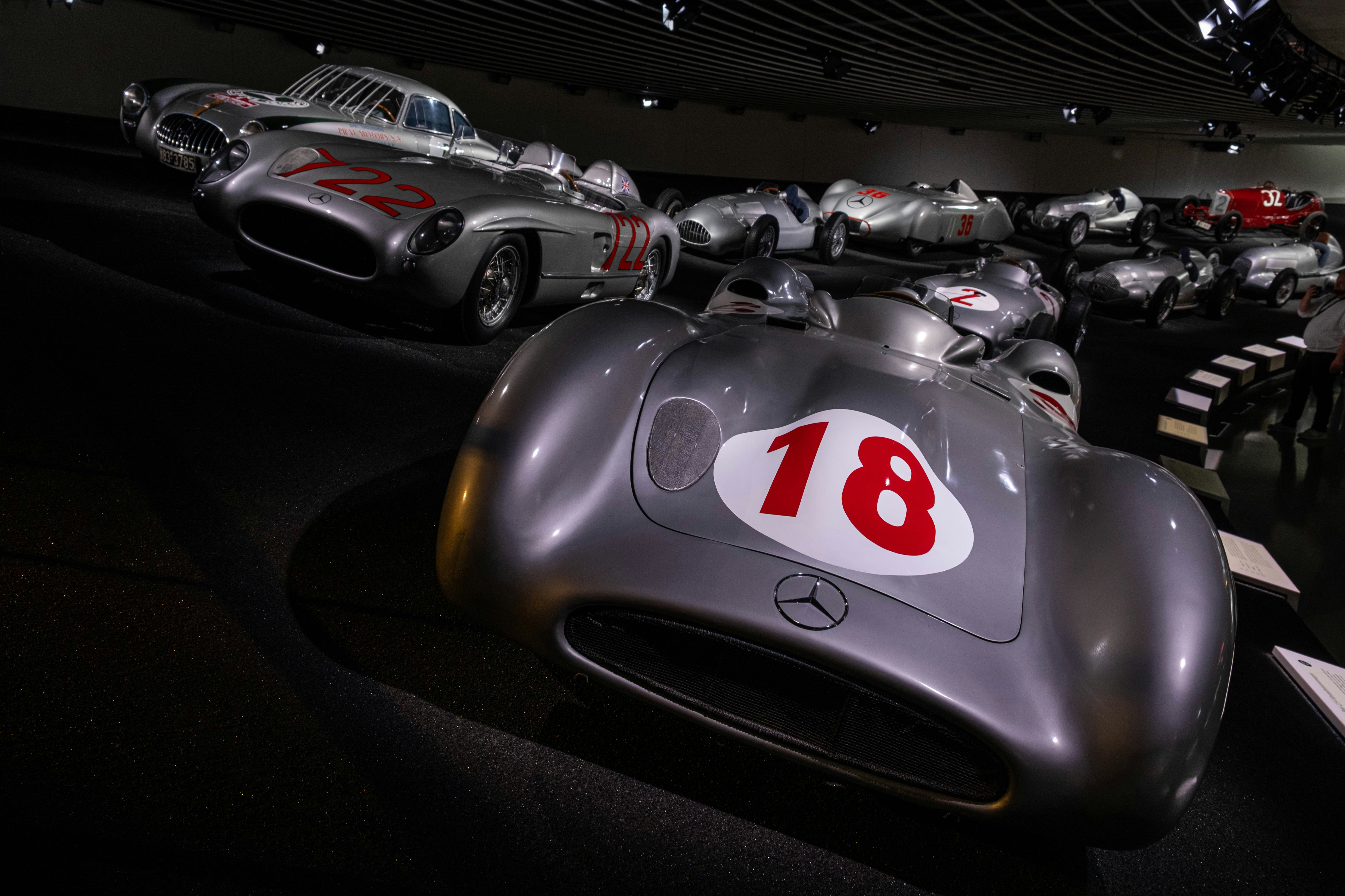 Carros de corrida de prata vintage exibidos em um ambiente de museu.