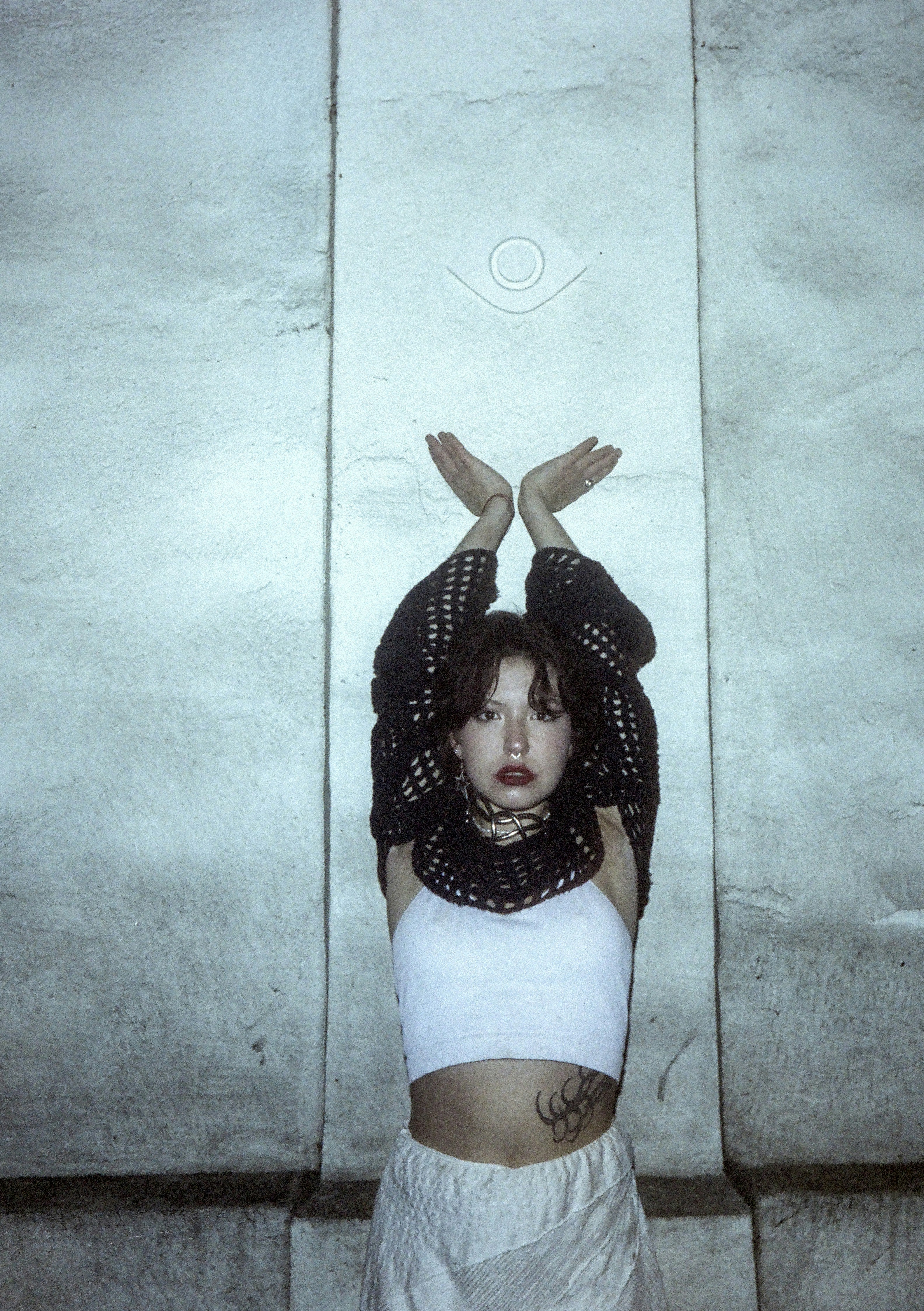 Woman with arms raised in front of stone wall